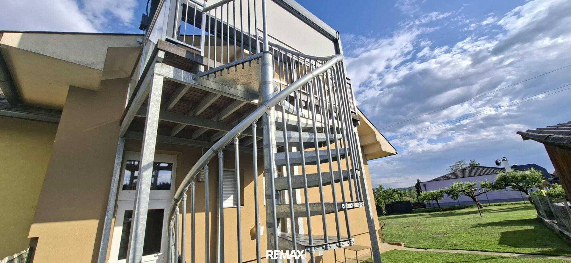Metall-Wendeltreppe, die zu einem oberen Balkon des Hauses führt.