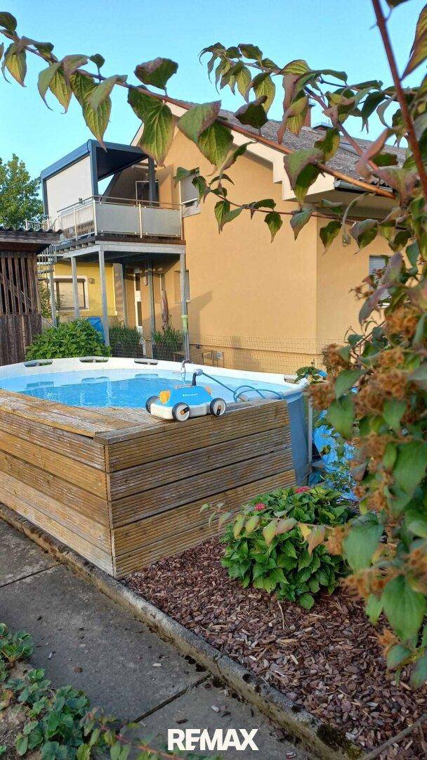 Eingelassener Aufstellpool im Gartenbereich, umgeben von Holzverkleidung und Pflanzen.
