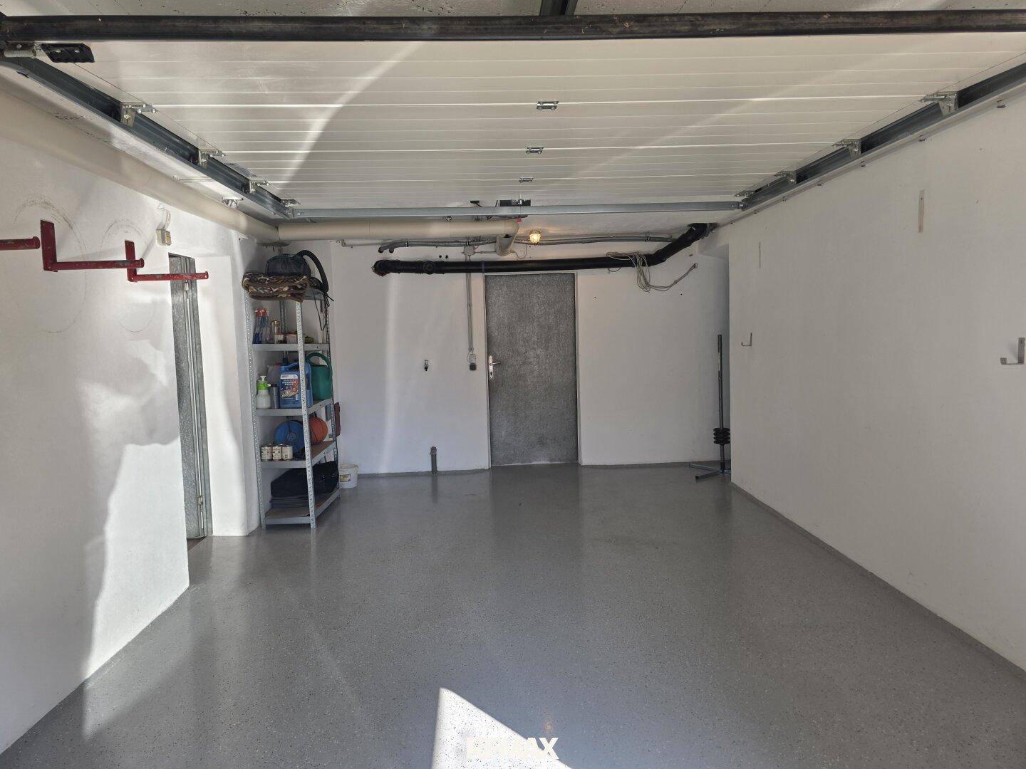 Geräumige Garage mit Betonboden und ausreichend Platz für Fahrzeuge und Lagerung.