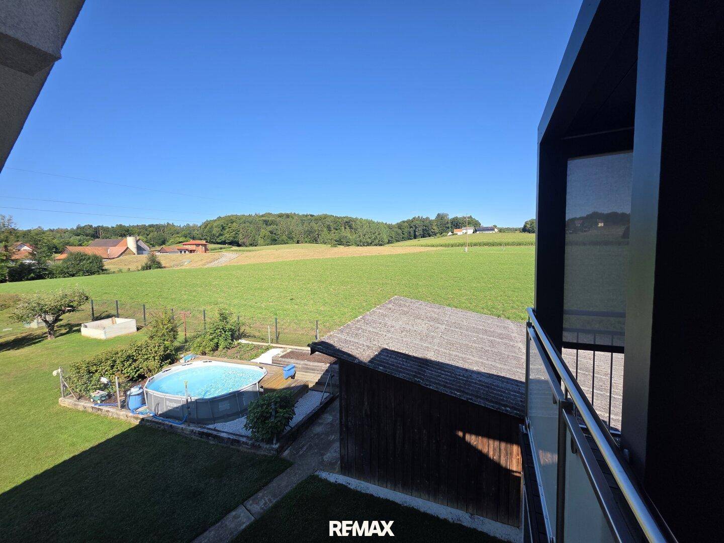 Panoramablick vom Balkon auf den Poolbereich und die weiten Felder der Umgebung.