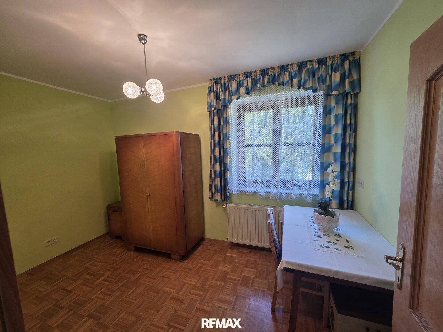 Schlafzimmer mit grün gestrichenen Wänden, Holzboden und einem Fenster.