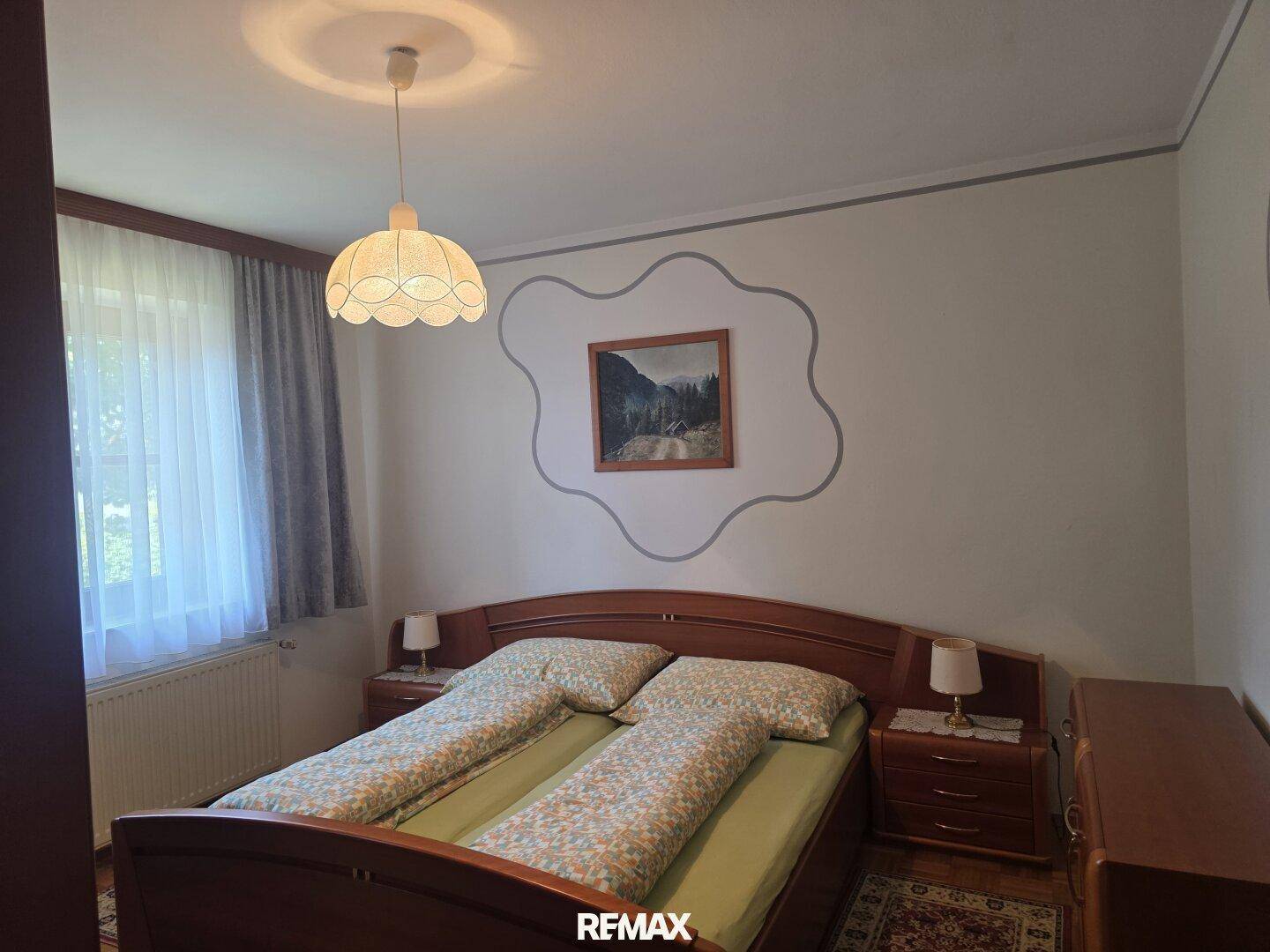 Gemütliches Schlafzimmer mit Doppelbett, Nachttischen und einem Fenster.