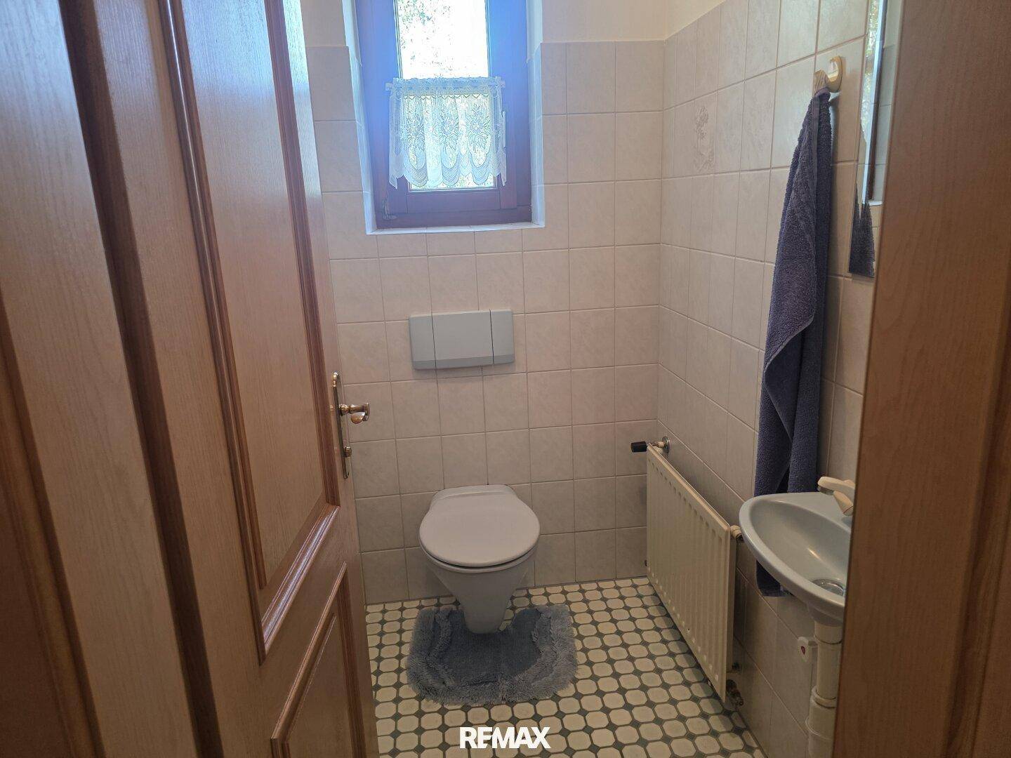 Kleines Gäste-WC mit Fenster, Wand-WC und Handwaschbecken.