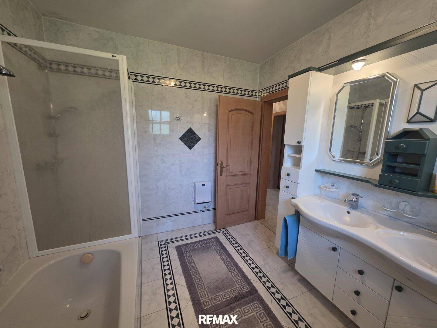 Badezimmer mit Doppelwaschbecken, Spiegelschrank und Dusche in hellem Design.
