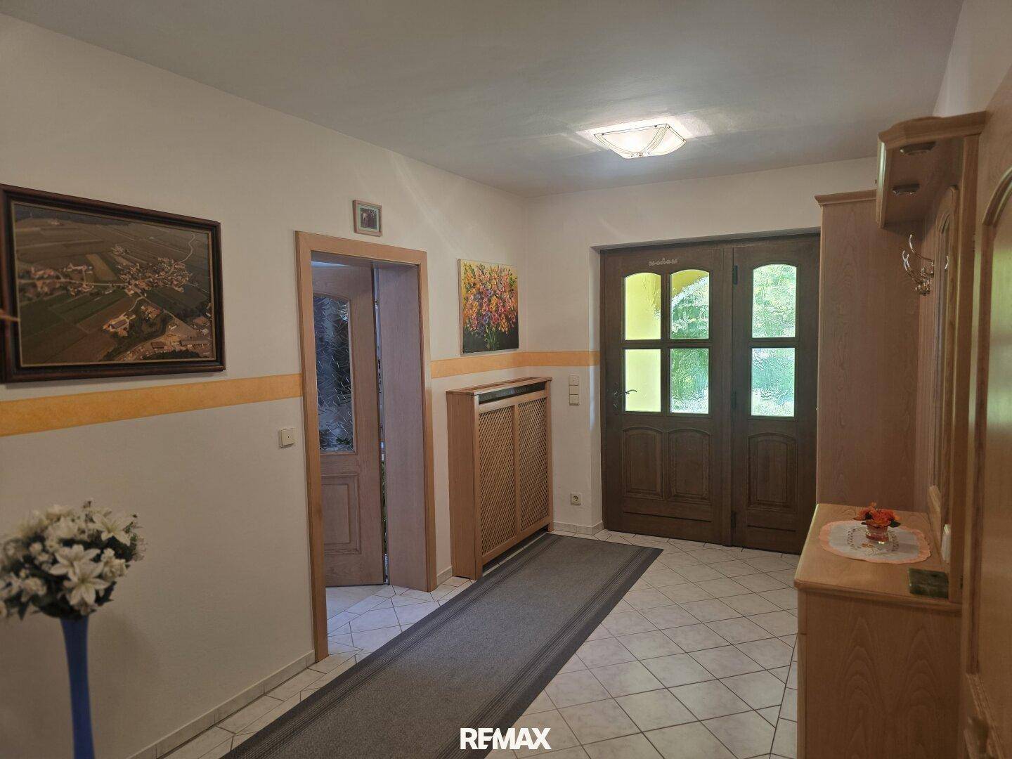 Heller Eingangsbereich mit Fliesenboden, Holzmöbeln und einer Garderobe.