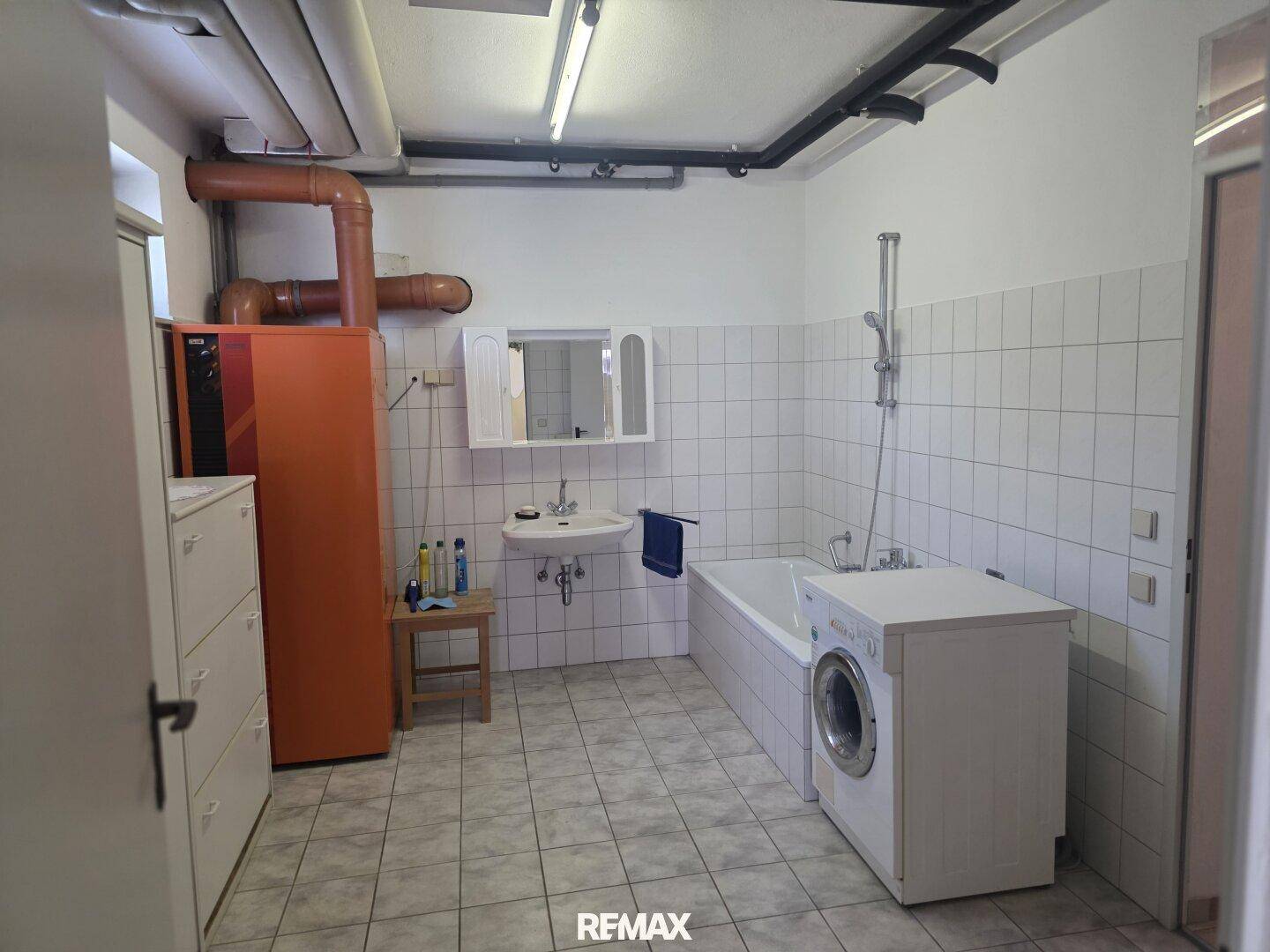 Hauswirtschaftsraum im Keller mit Waschmaschine, Badewanne und Heizungsanlage.
