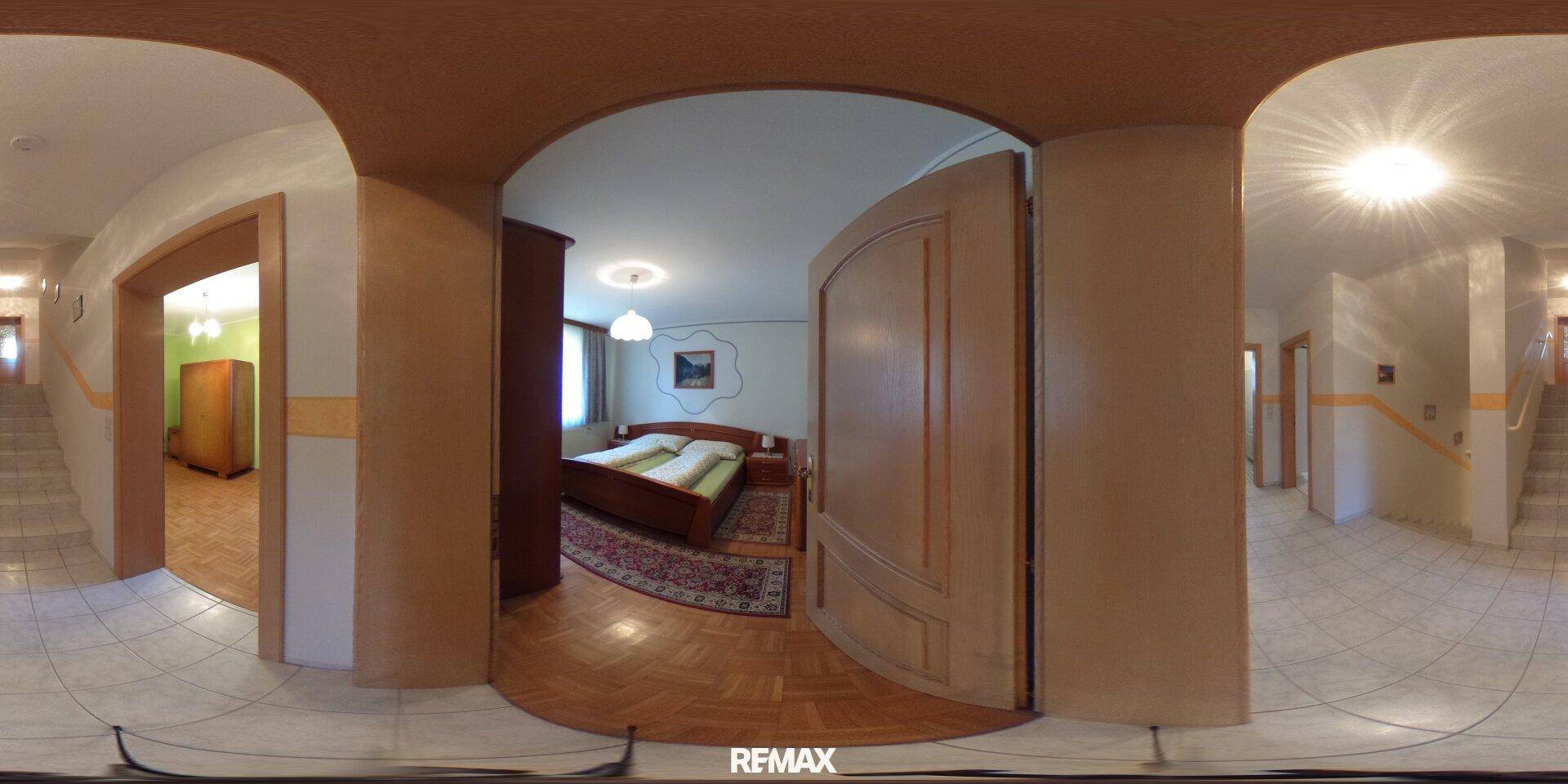 Gemütliches Schlafzimmer mit Holzbett, Parkettboden und Kleiderschrank, zugänglich über einen Bogen.