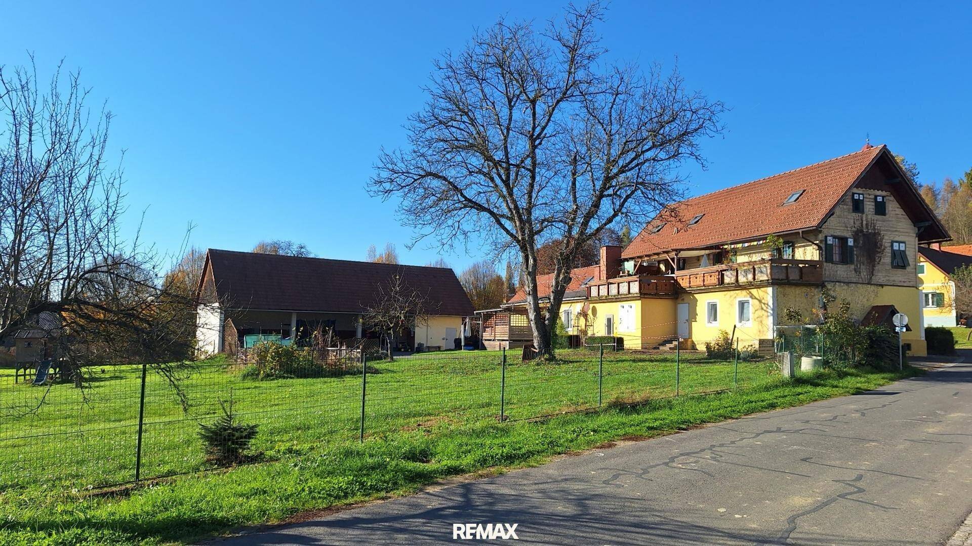 Weitläufiges Grundstück mit gelbem Haus, Scheune und kahlen Bäumen in ländlicher Umgebung.