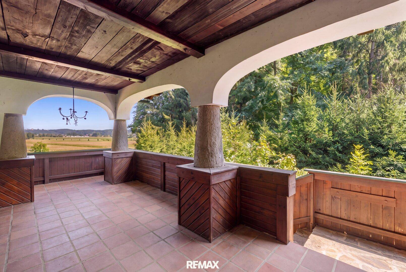 Geräumige überdachte Loggia mit Terrakottaboden und Holzbalkendecke, ideal für entspannte Stunden.