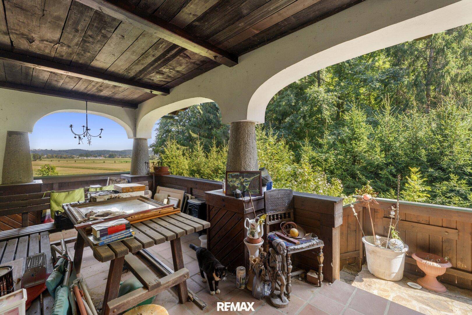 Überdachte Loggia mit Terrakottaboden, Holzbalkendecke und weitem Blick über die Landschaft.