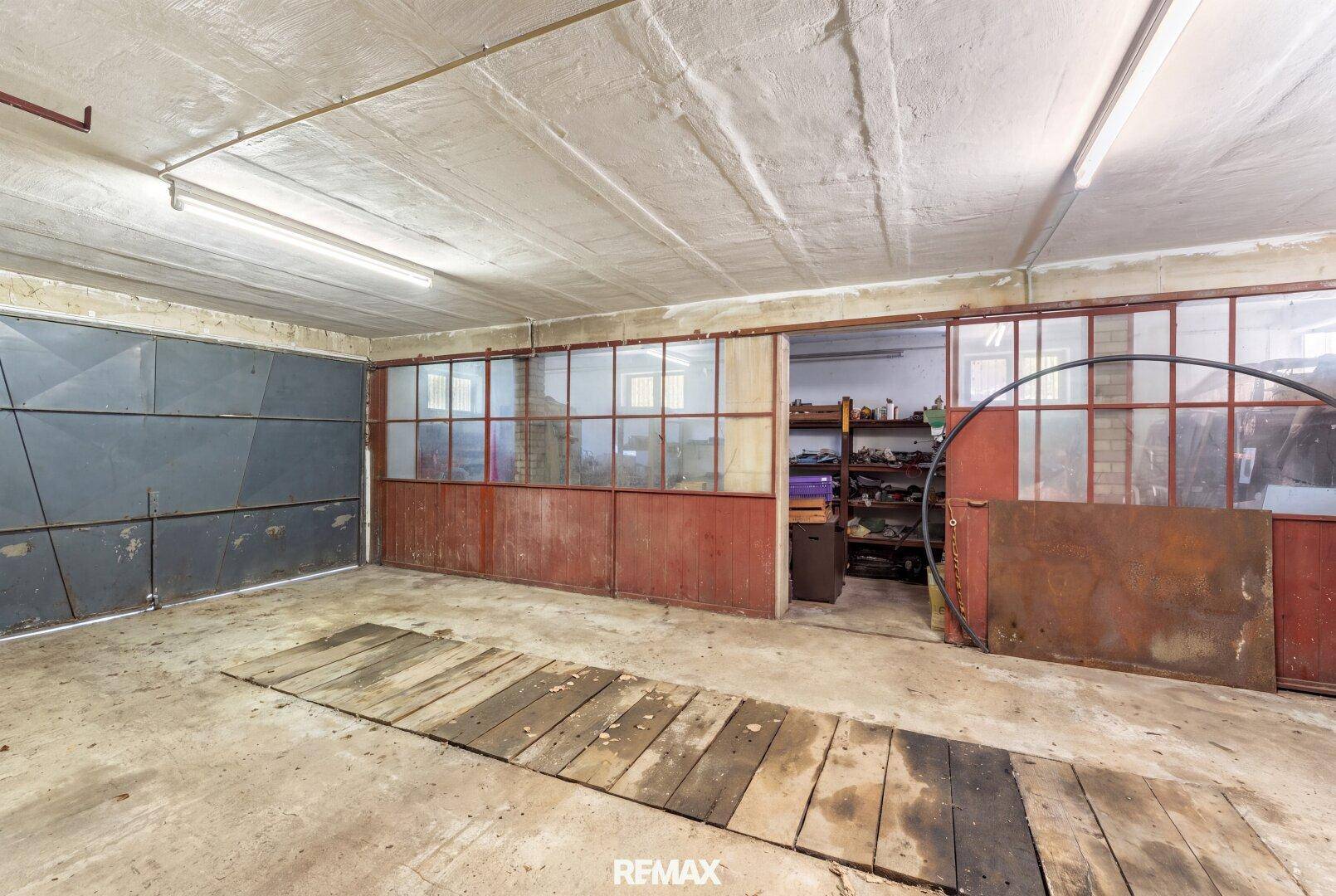 Geräumige, aufgeräumte Garage mit Betonboden und großem Tor, ideal für Fahrzeuge oder als Werkstatt.