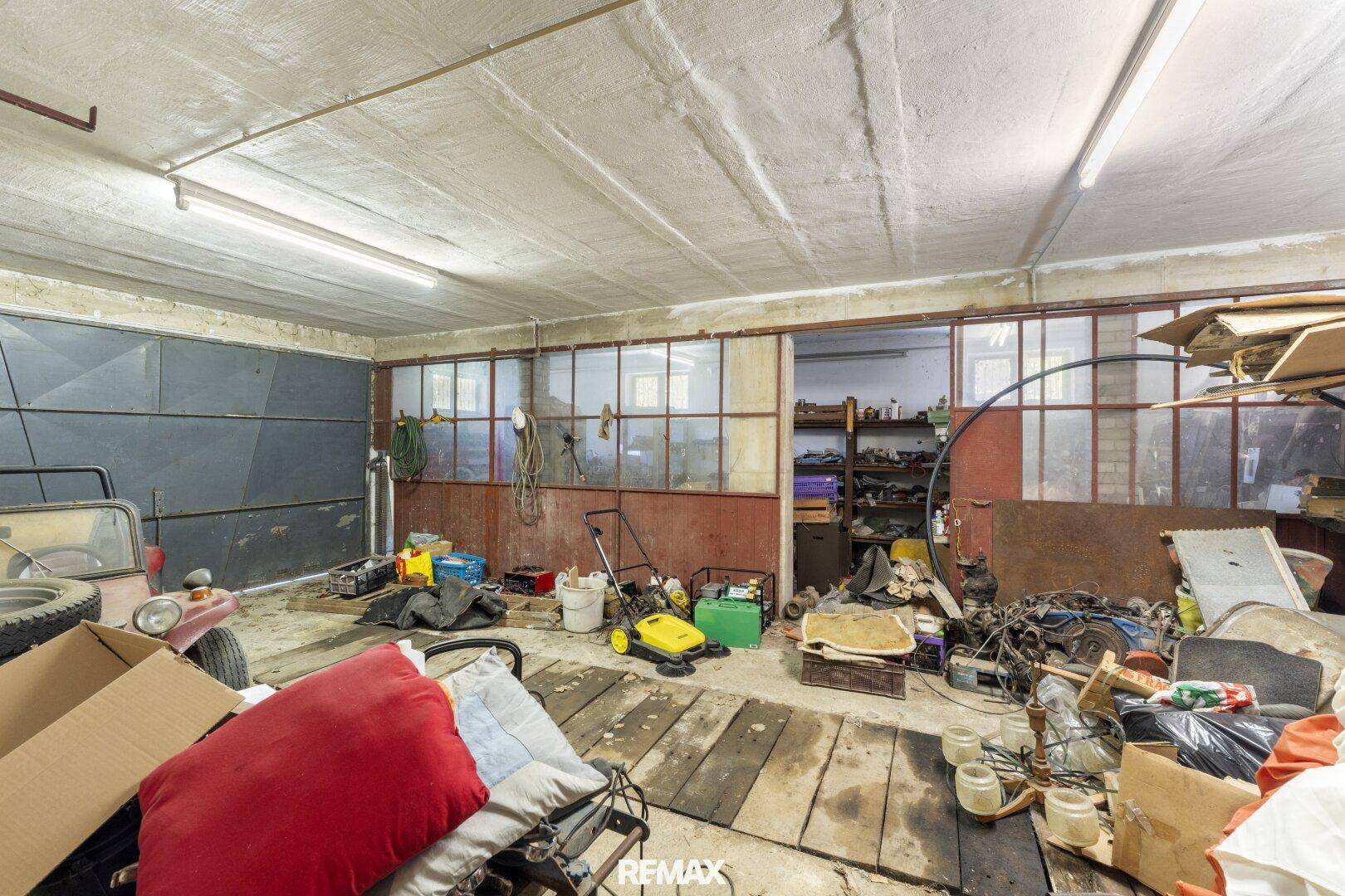 Unordentliche Garage mit Werkzeugen, Geräten und einem Fahrzeug, bereit für Reparaturen oder Lagerung.