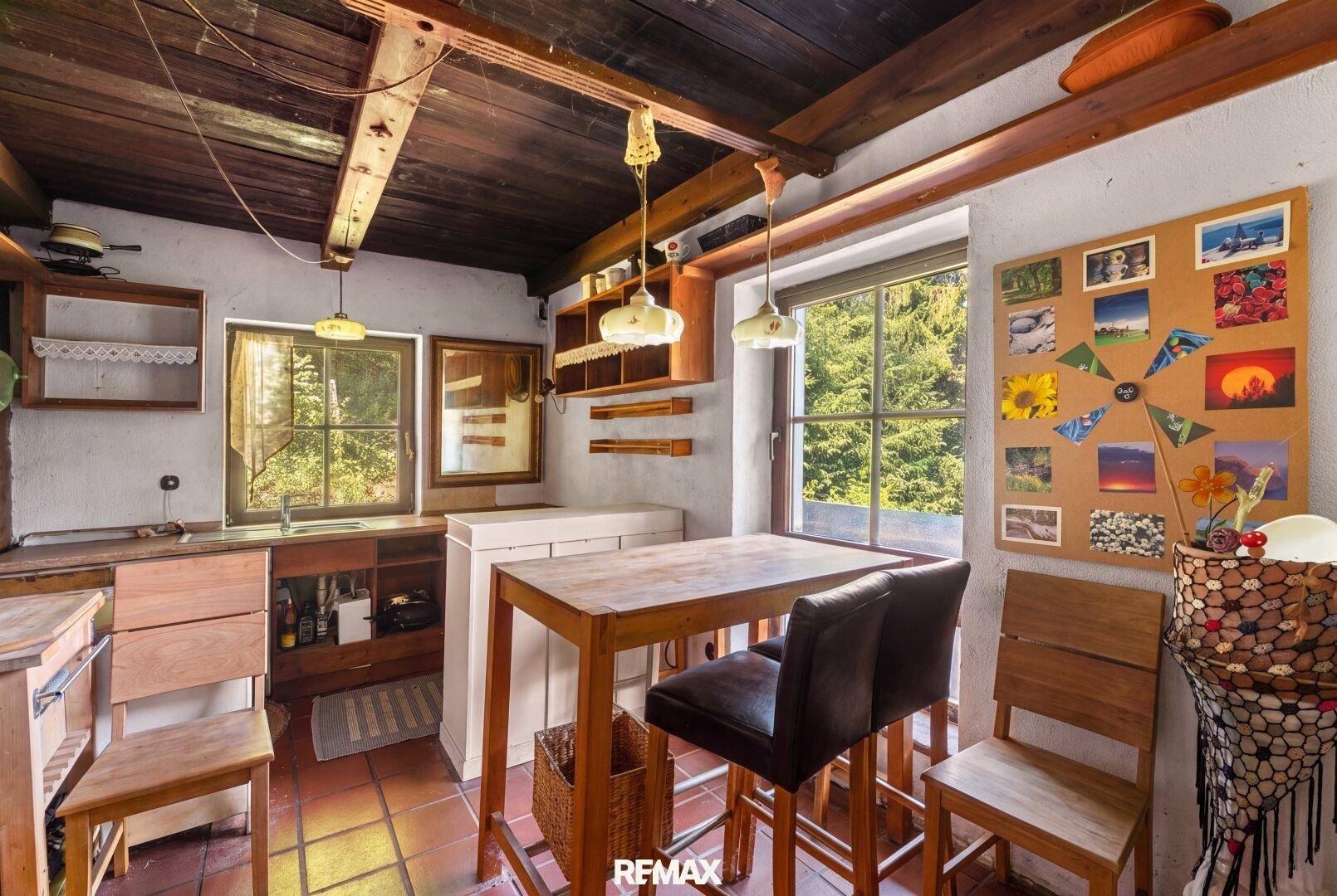 Gemütliche Küche mit Holzbalkendecke, Terrakottaboden und einem kleinen Essbereich am Fenster.