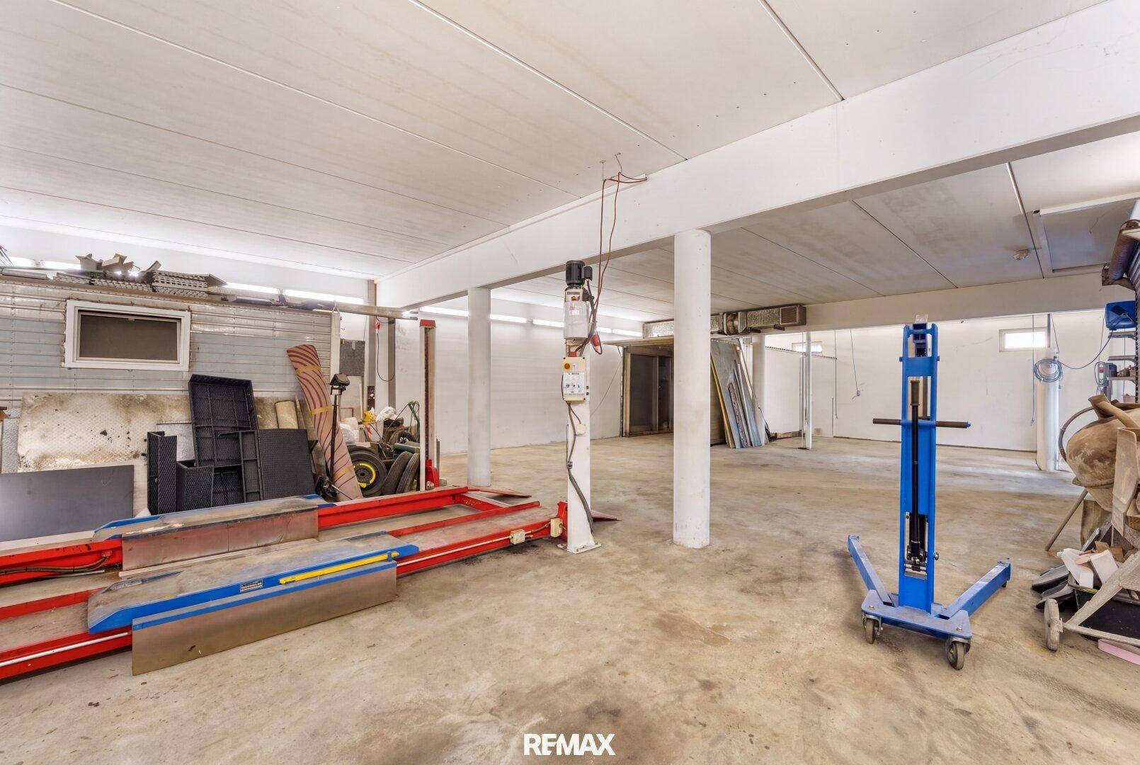 Aufgeräumte Werkstatt mit Betonboden und einigen Geräten, bietet viel Platz für verschiedene Projekte.