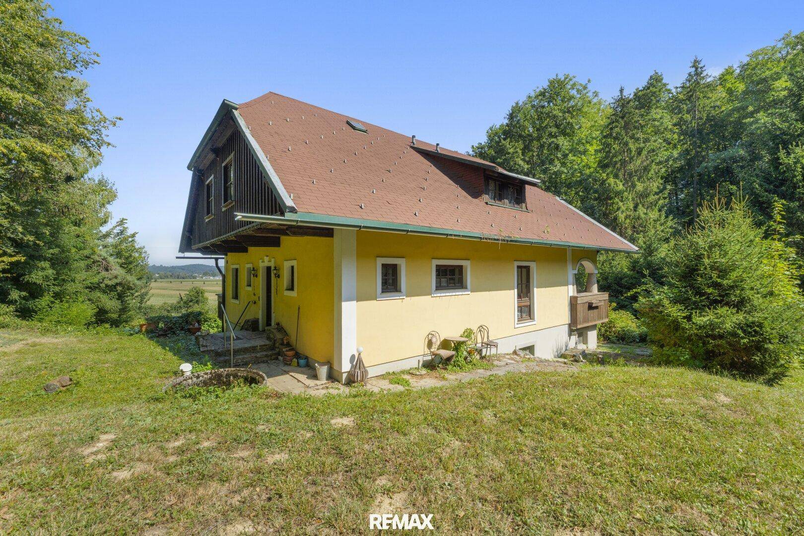 Seitenansicht des gelben Hauses mit kleinem Balkon und Blick auf die weite Landschaft.