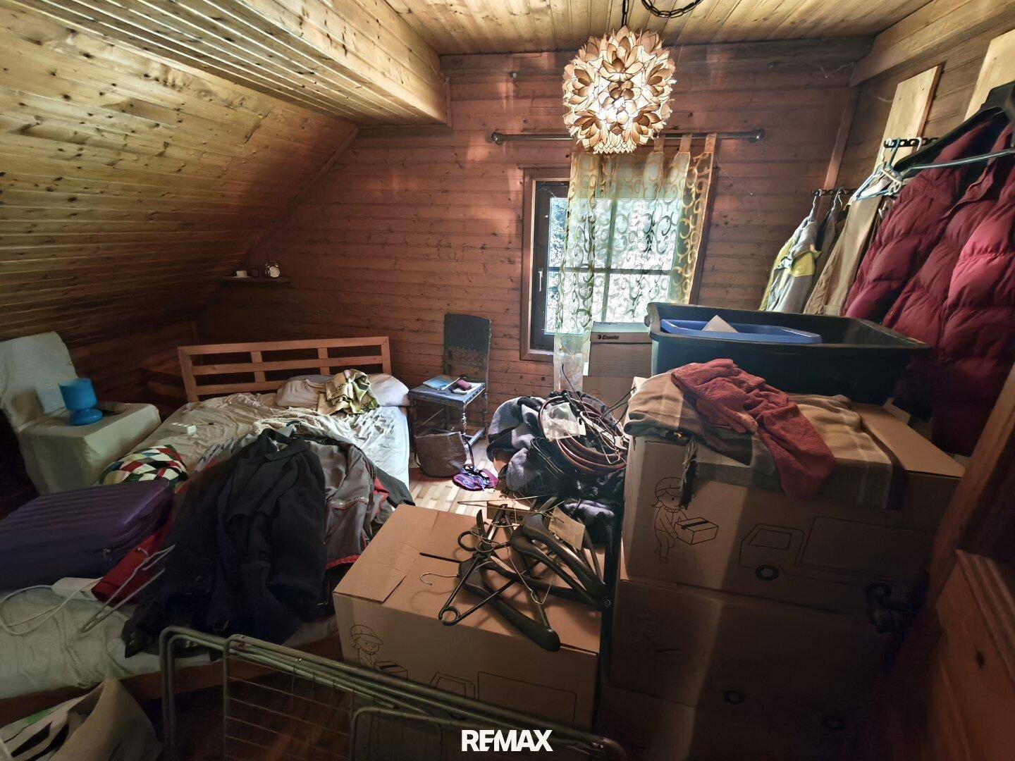Gemütliches Schlafzimmer im Dachgeschoss mit Holzverkleidung, Fenster und Dachschrägen.