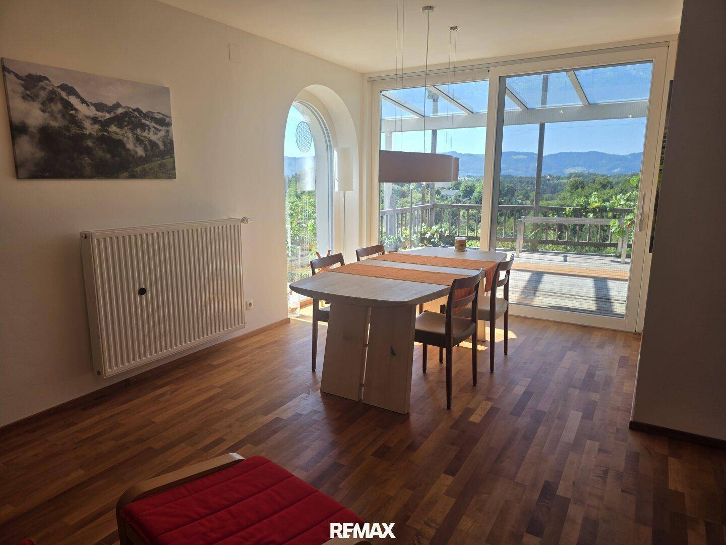 Heller Essbereich mit Holzboden und großen Fenstern, die Zugang zur Terrasse und Weitblick bieten.