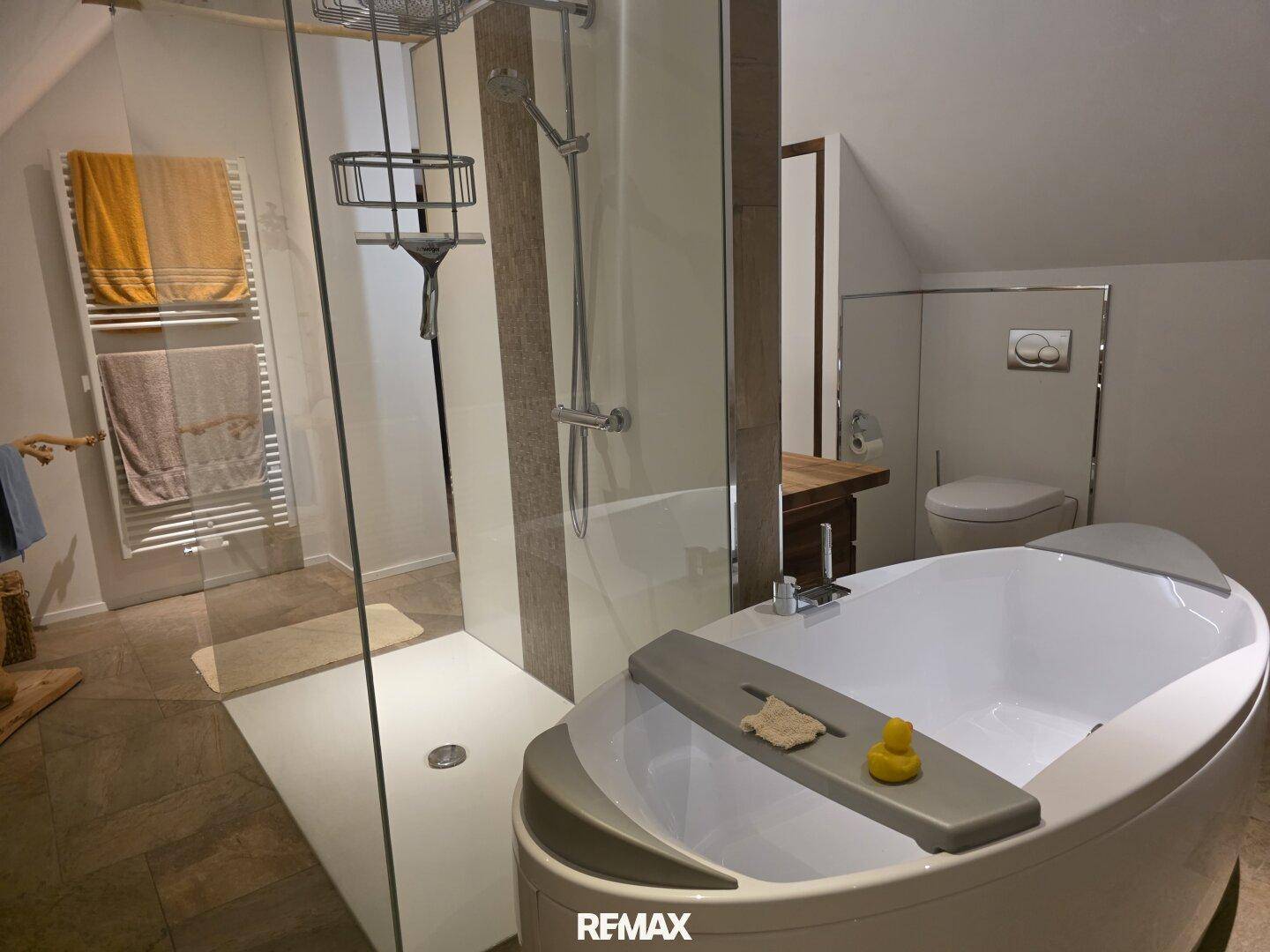 Detailansicht des Dachgeschossbades mit freistehender Wanne, großer Dusche und beheiztem Handtuchhalter.