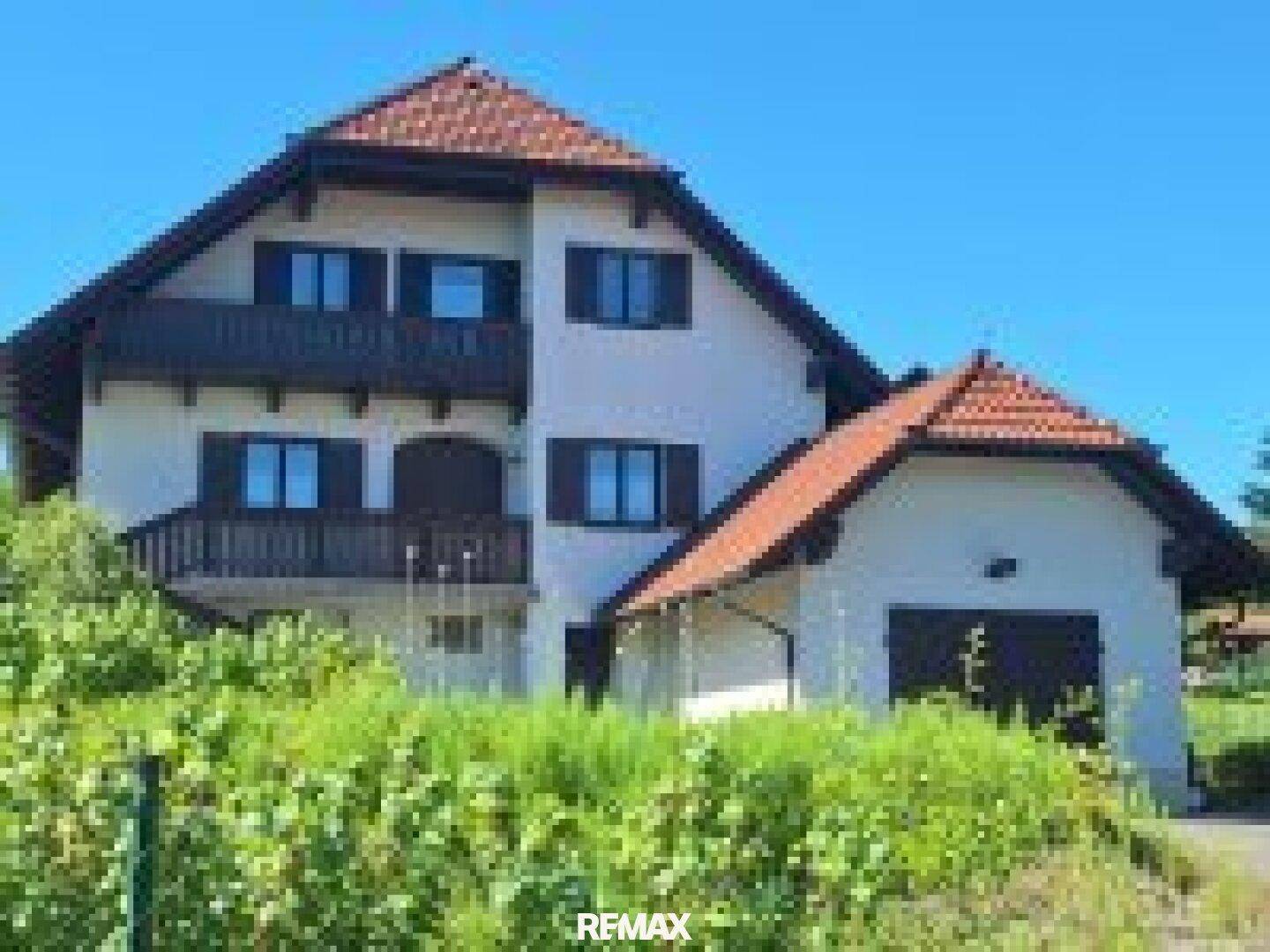 Das Einfamilienhaus präsentiert sich mit mehreren Balkonen und einer integrierten Garage unter blauem Himmel.