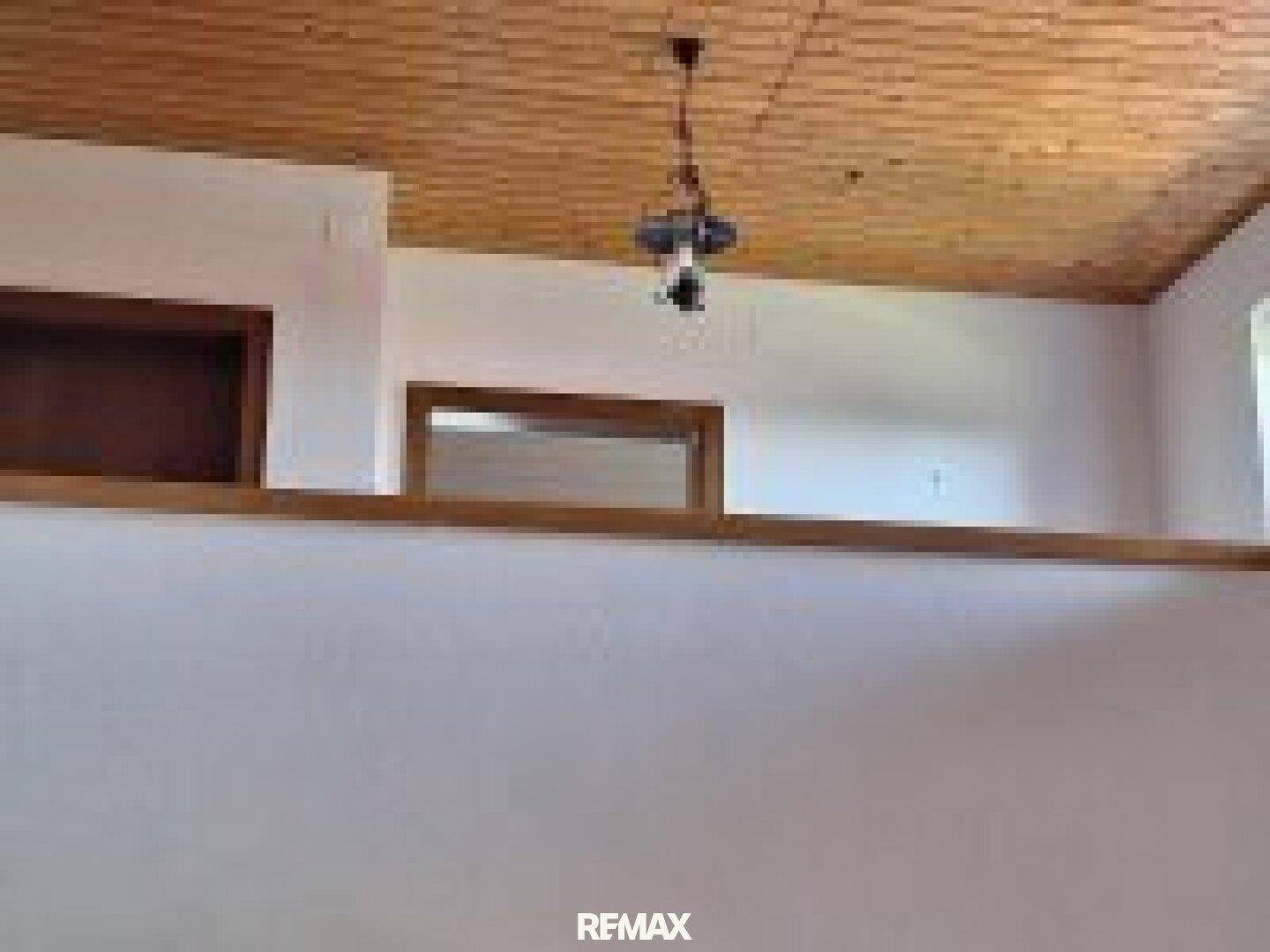 Offener Bereich im Obergeschoss mit Holzdecke und Blick auf einen darunterliegenden Raum.
