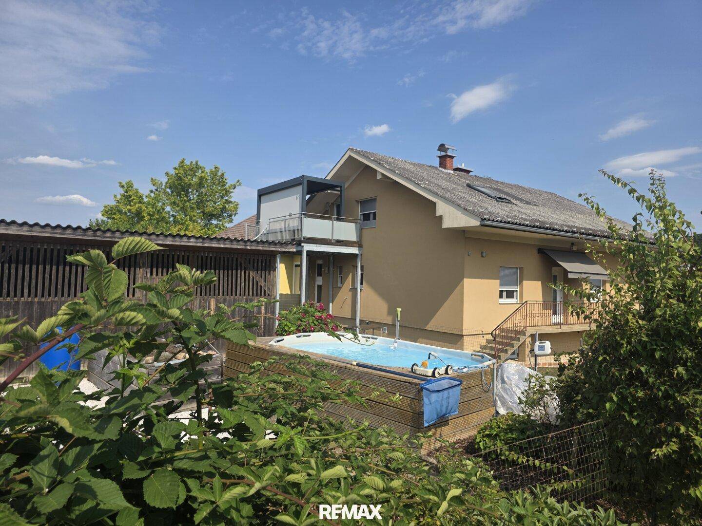 Gartenbereich mit einem eingelassenen Aufstellpool und Blick auf die umliegende Landschaft.