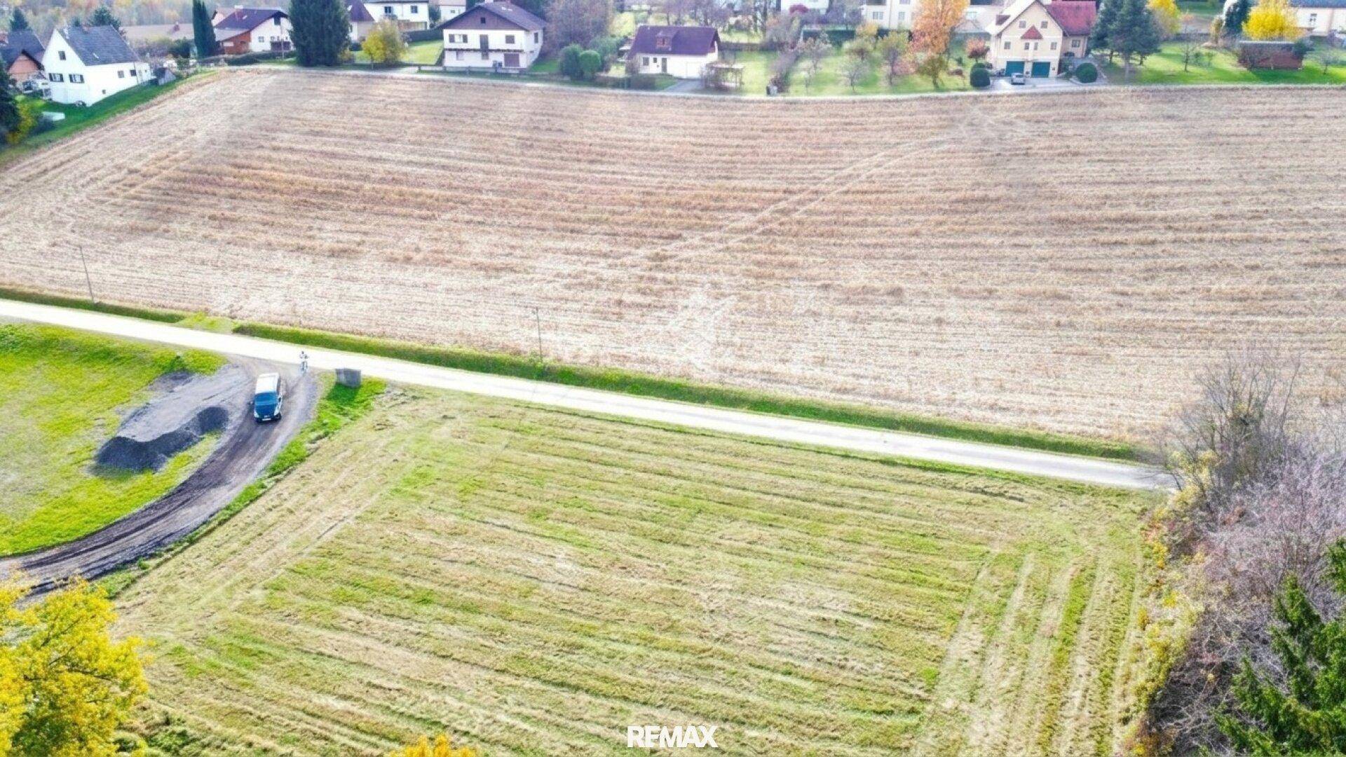 Luftaufnahme eines weitläufigen Grundstücks mit angrenzenden Feldern und Häusern im Hintergrund.