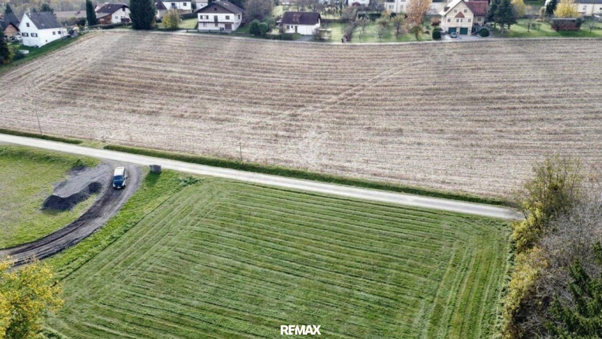 Übersichtliche Luftaufnahme eines Grundstücks mit Feldern, Straße und Häusern in der Ferne.