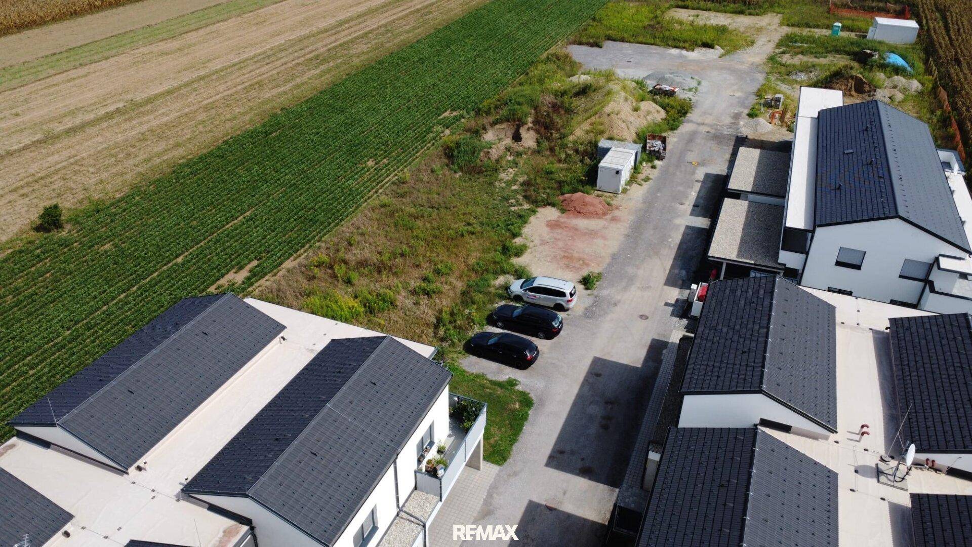 Übersicht aus der Vogelperspektive auf eine Wohnsiedlung mit angrenzenden landwirtschaftlichen Flächen.