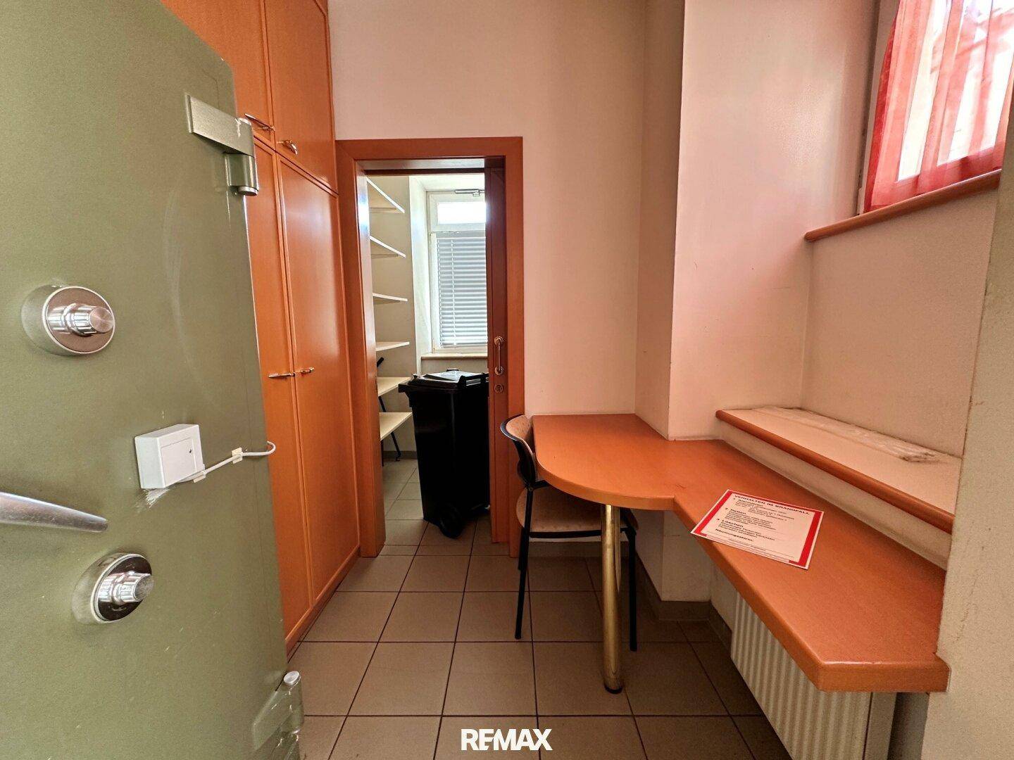 Kleiner Büroraum mit eingebauten Schränken, einem Tresor und einem Fenster.