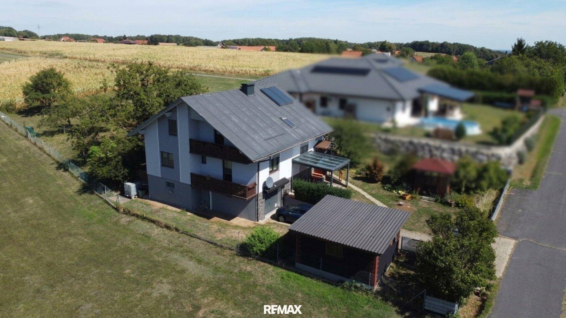 Weitläufige Luftaufnahme des Hauses mit Balkonen, Carport und angrenzenden Feldern.