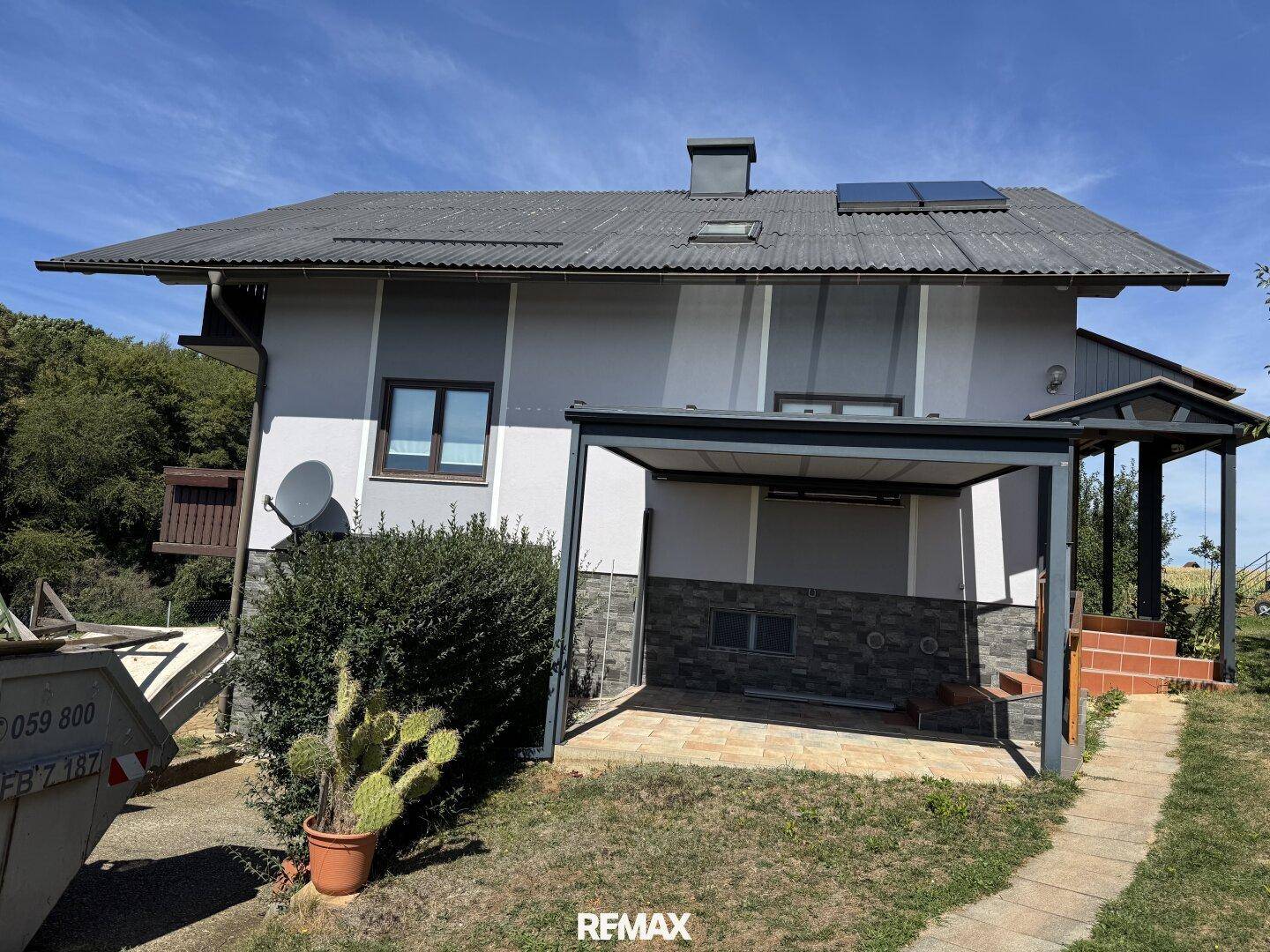 Ansicht des Hauses mit Carport, Steindetails und einem Kaktus im Topf vor der Fassade.