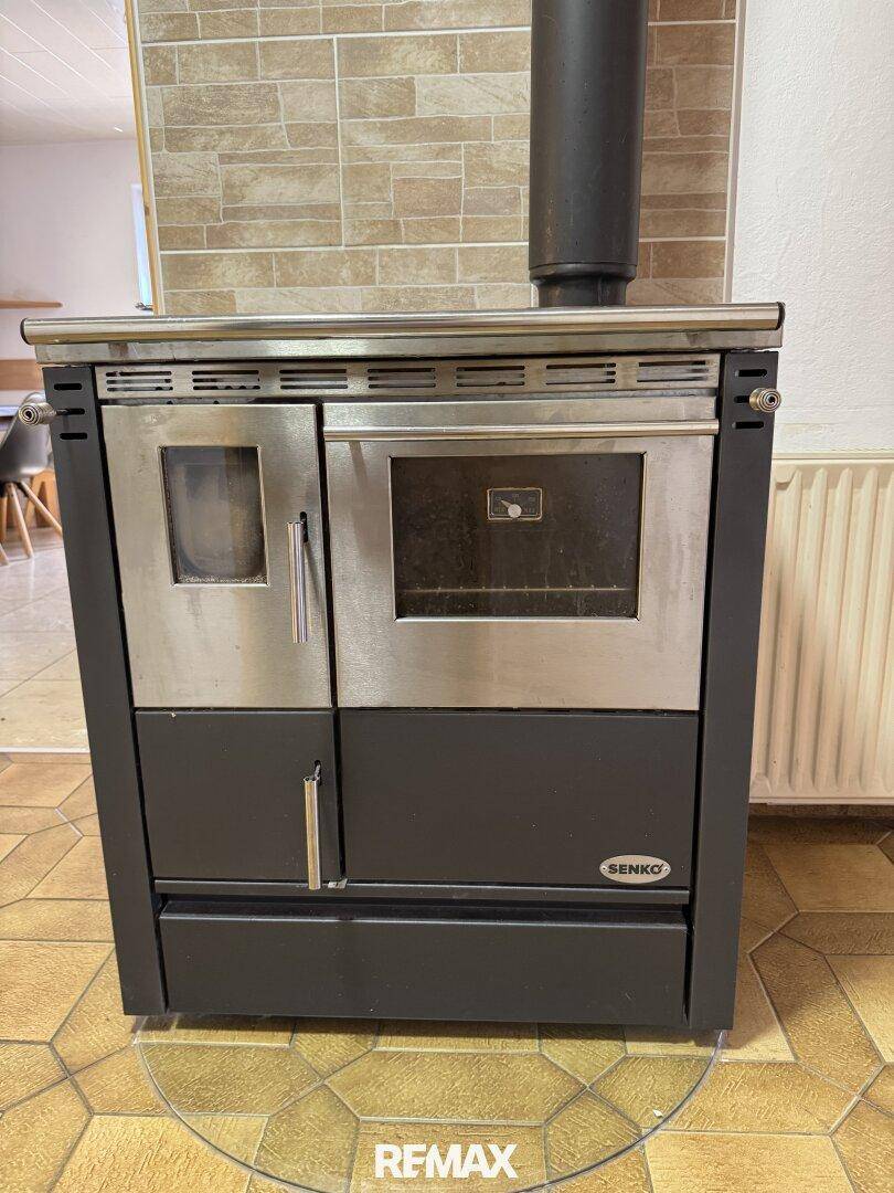 Detailansicht eines modernen Holzofens mit Backfach und Kochplatte.