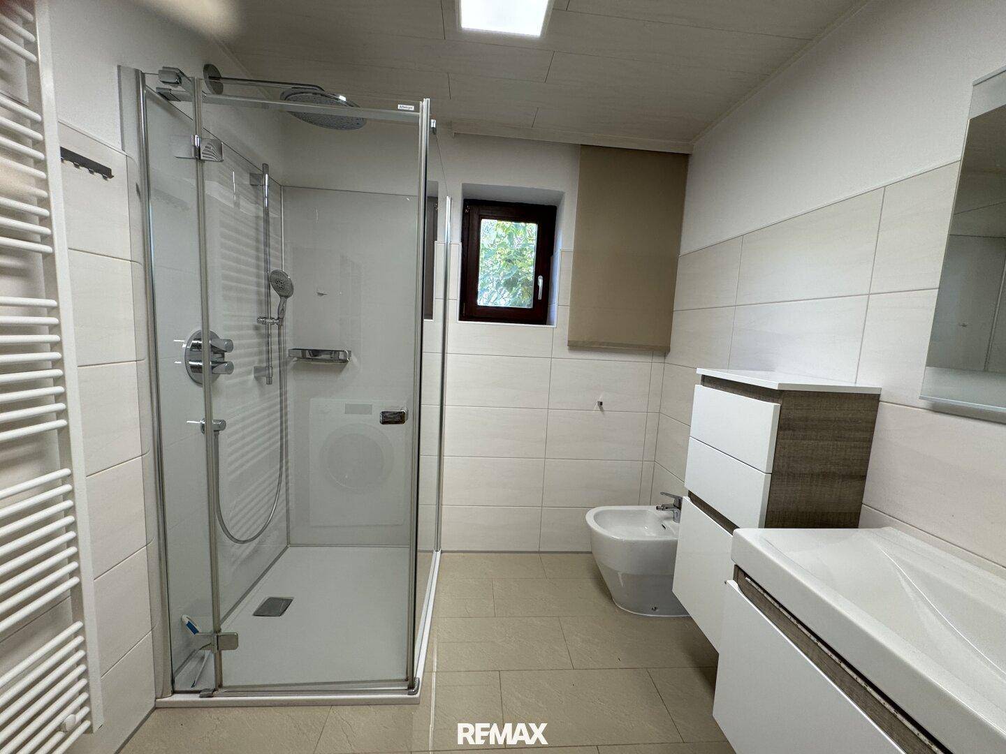 Modernes Badezimmer mit ebenerdiger Dusche, Bidet und beheiztem Handtuchhalter.