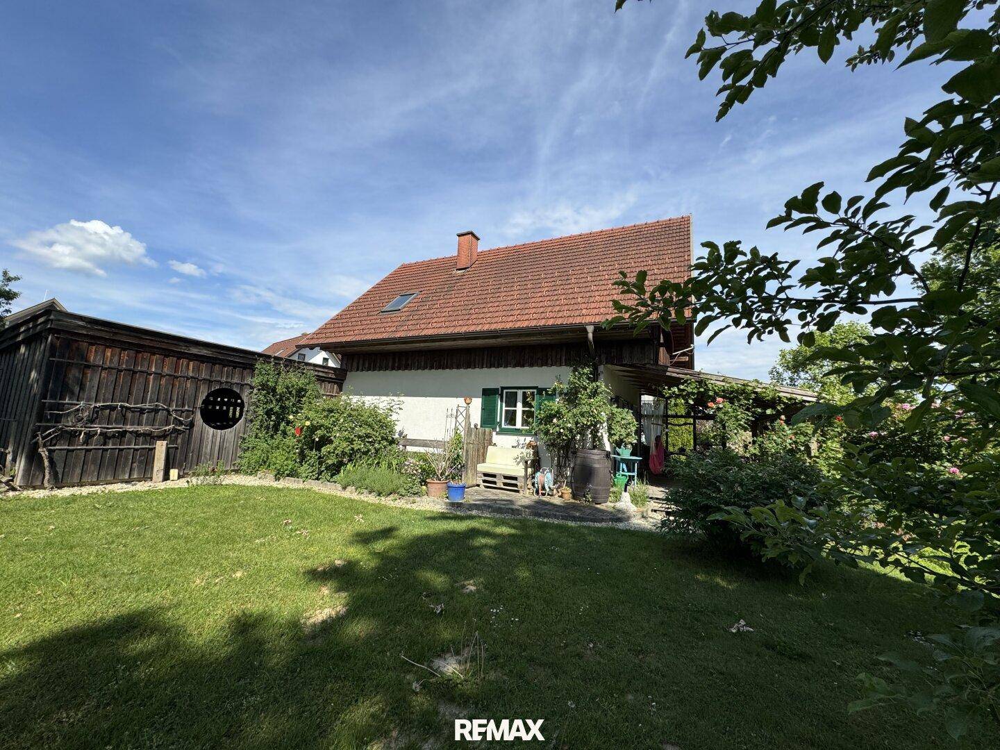 Weitläufiger Gartenbereich neben dem Haus mit Rasenfläche, Sträuchern und einem rustikalen Holzschuppen.