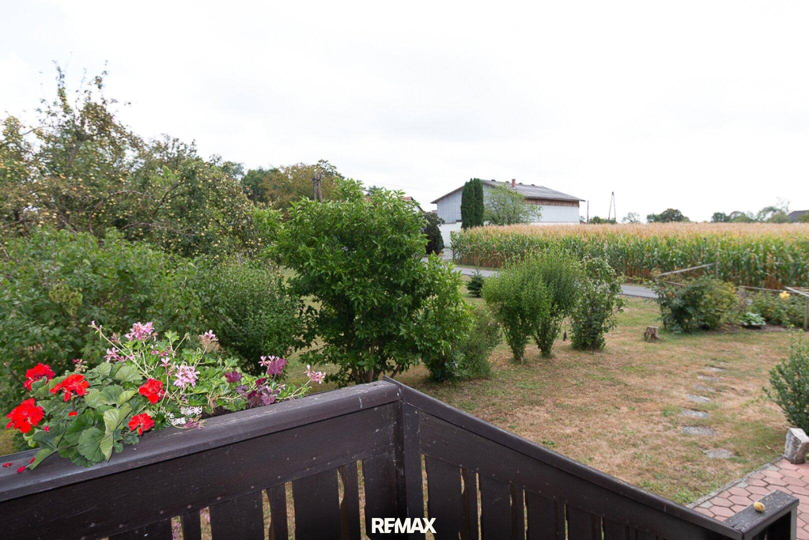 Blick von der Terrasse oder dem Balkon auf den Garten und angrenzende Felder.