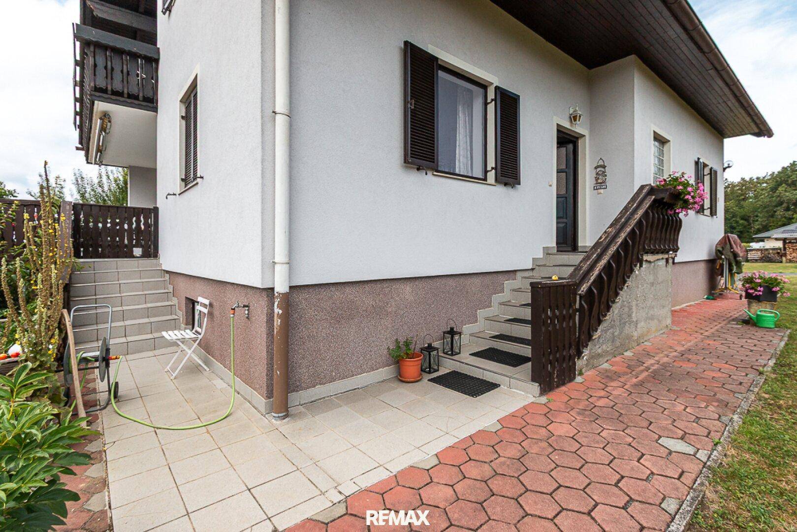 Seitlicher Eingangsbereich des Hauses mit Außentreppe und kleiner gepflasterter Fläche.