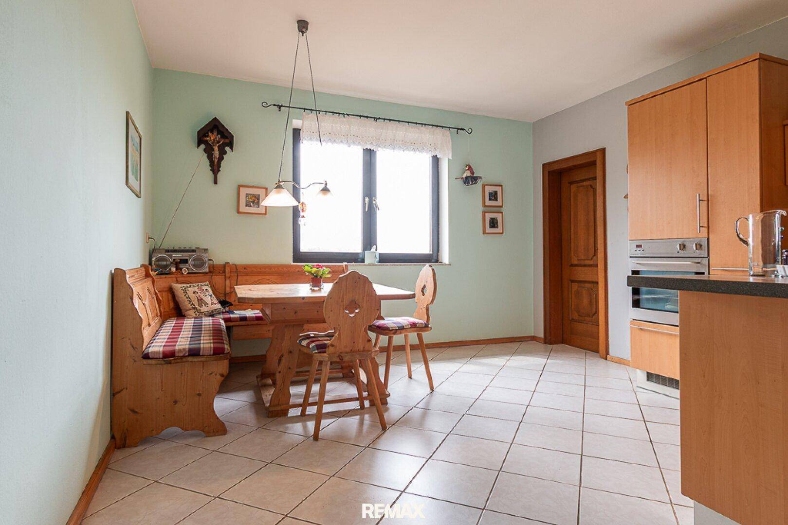 Gemütliche Essecke in der Küche mit traditionellen Holzmöbeln und Fenster.
