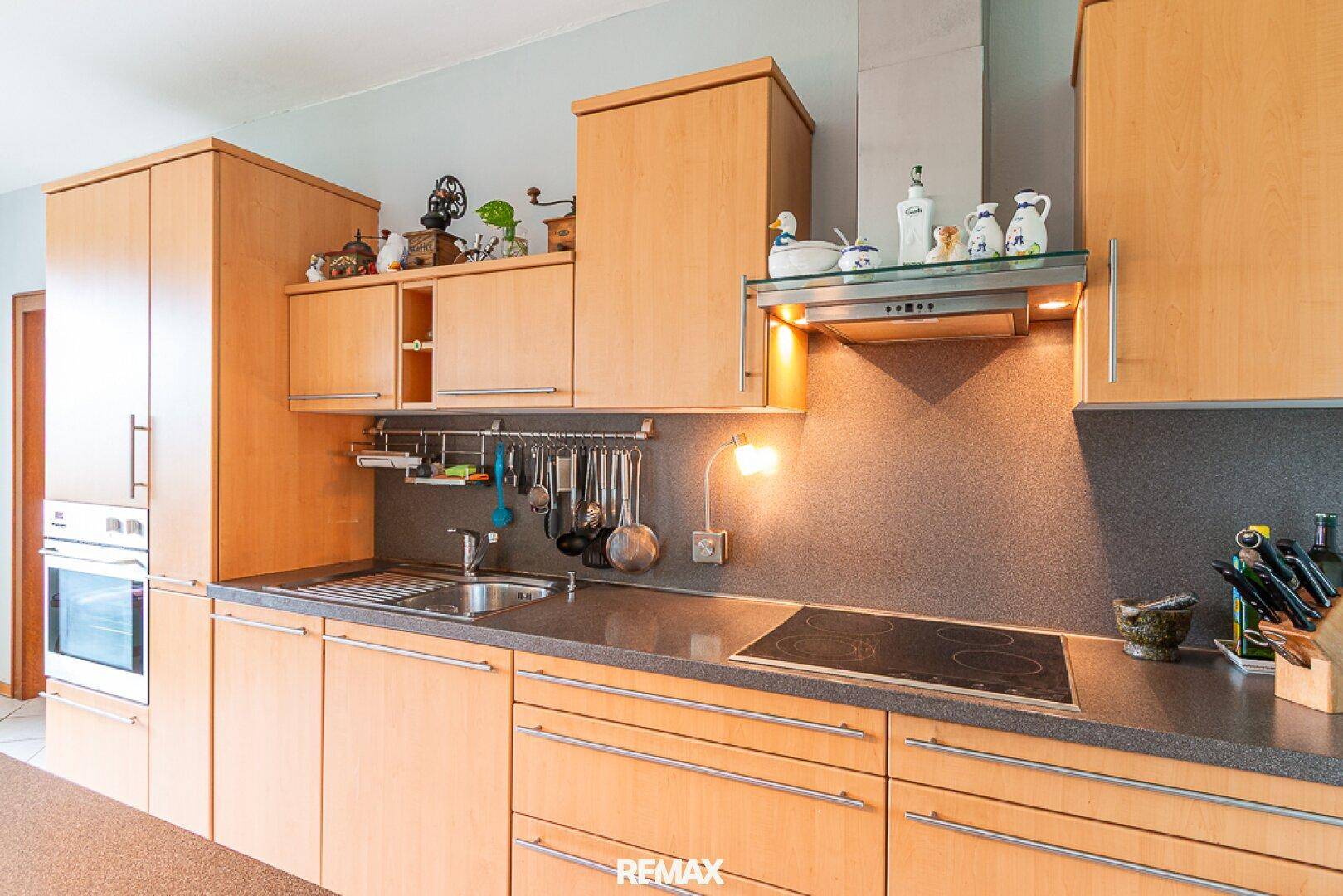 Küchenzeile mit Holzschränken, integriertem Backofen und Dunstabzugshaube.
