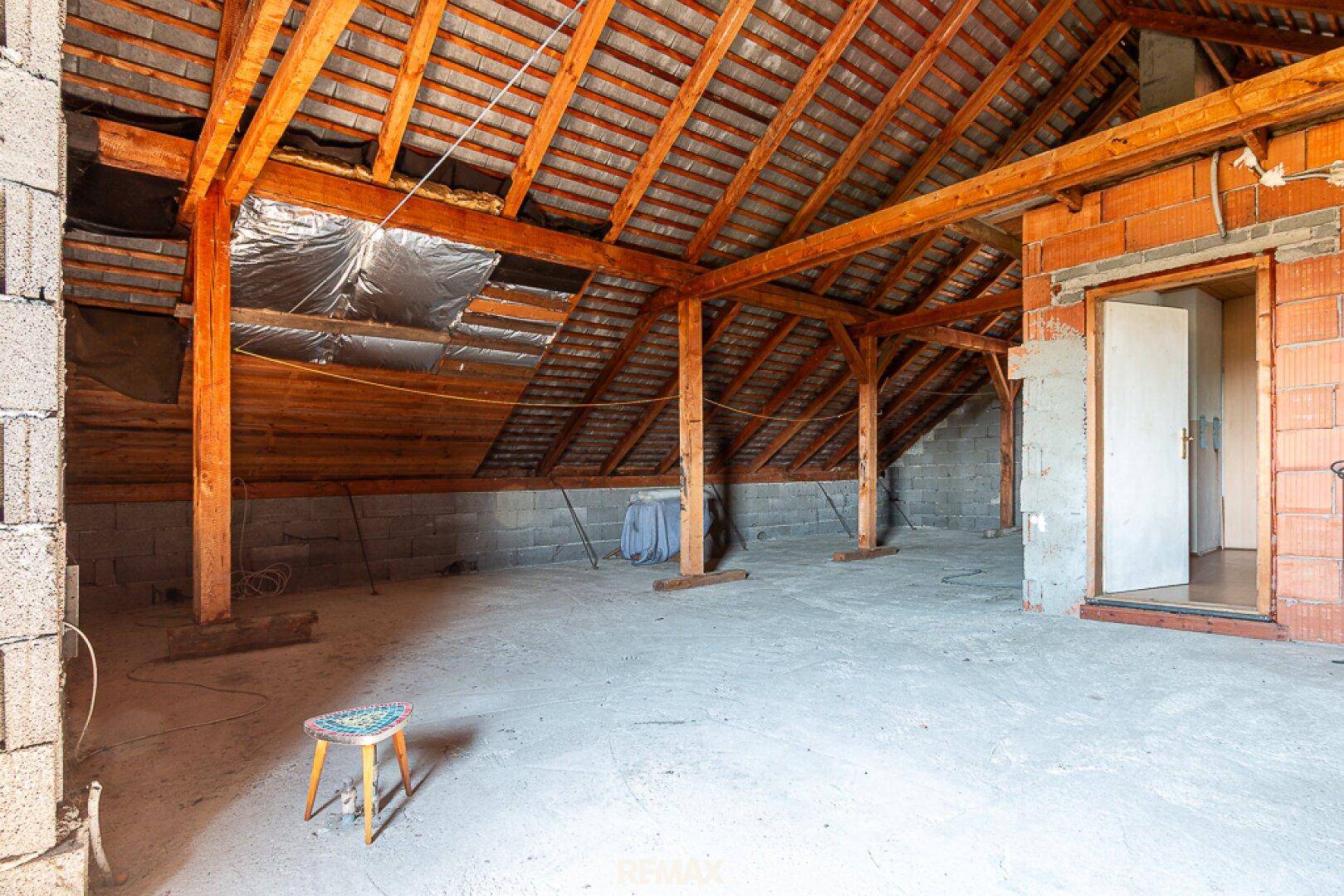 Geräumiger, unausgebauter Dachboden mit Holzdachstuhl und Ziegelwänden, viel Potenzial.