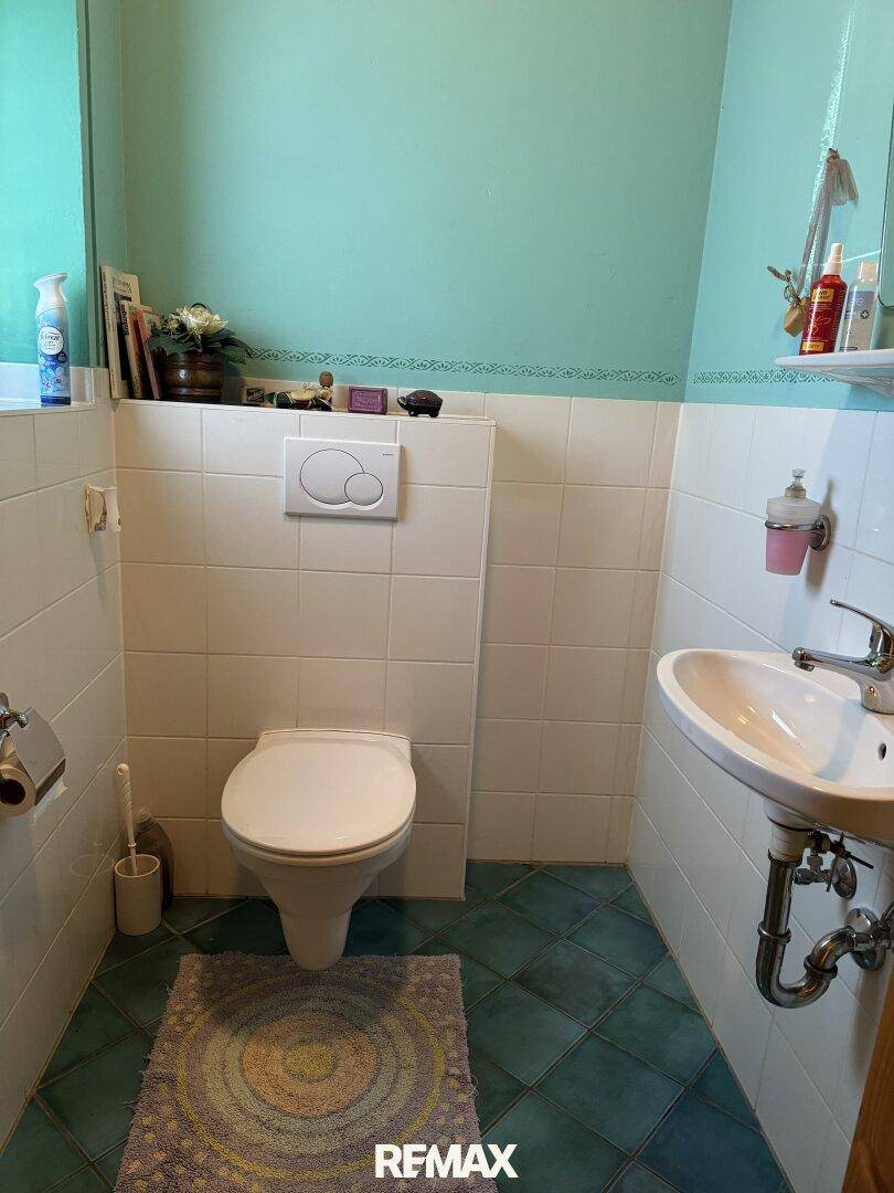 Kleines Gäste-WC mit hellblauen Wänden, weißen Fliesen und einem wandmontierten WC.