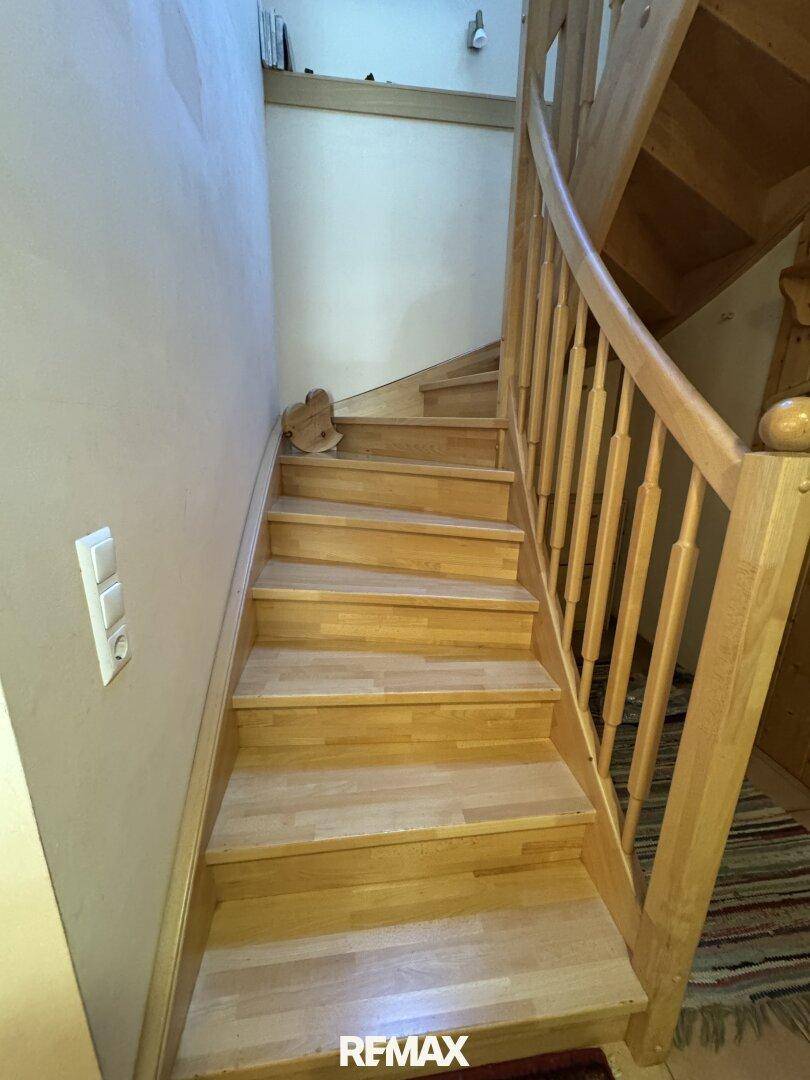 Helle Holztreppe mit Geländer, die in die oberen Stockwerke des Hauses führt.