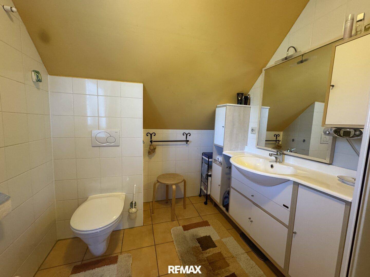 Badezimmer mit Dachschräge, WC, Waschtisch und Spiegelschrank, in gutem Zustand.