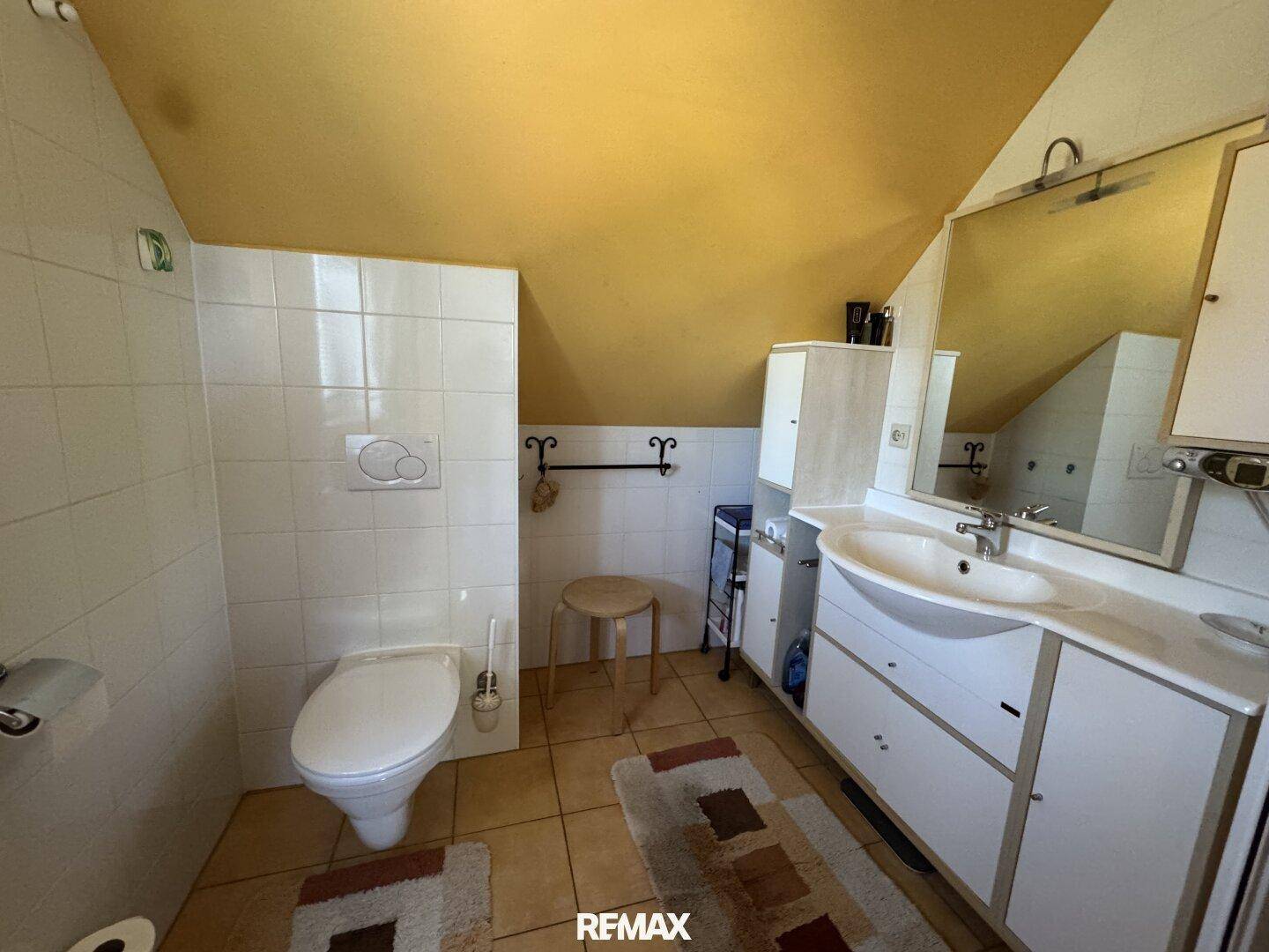 Badezimmer mit Dachschräge, WC, Waschtisch und Spiegelschrank, in gutem Zustand.