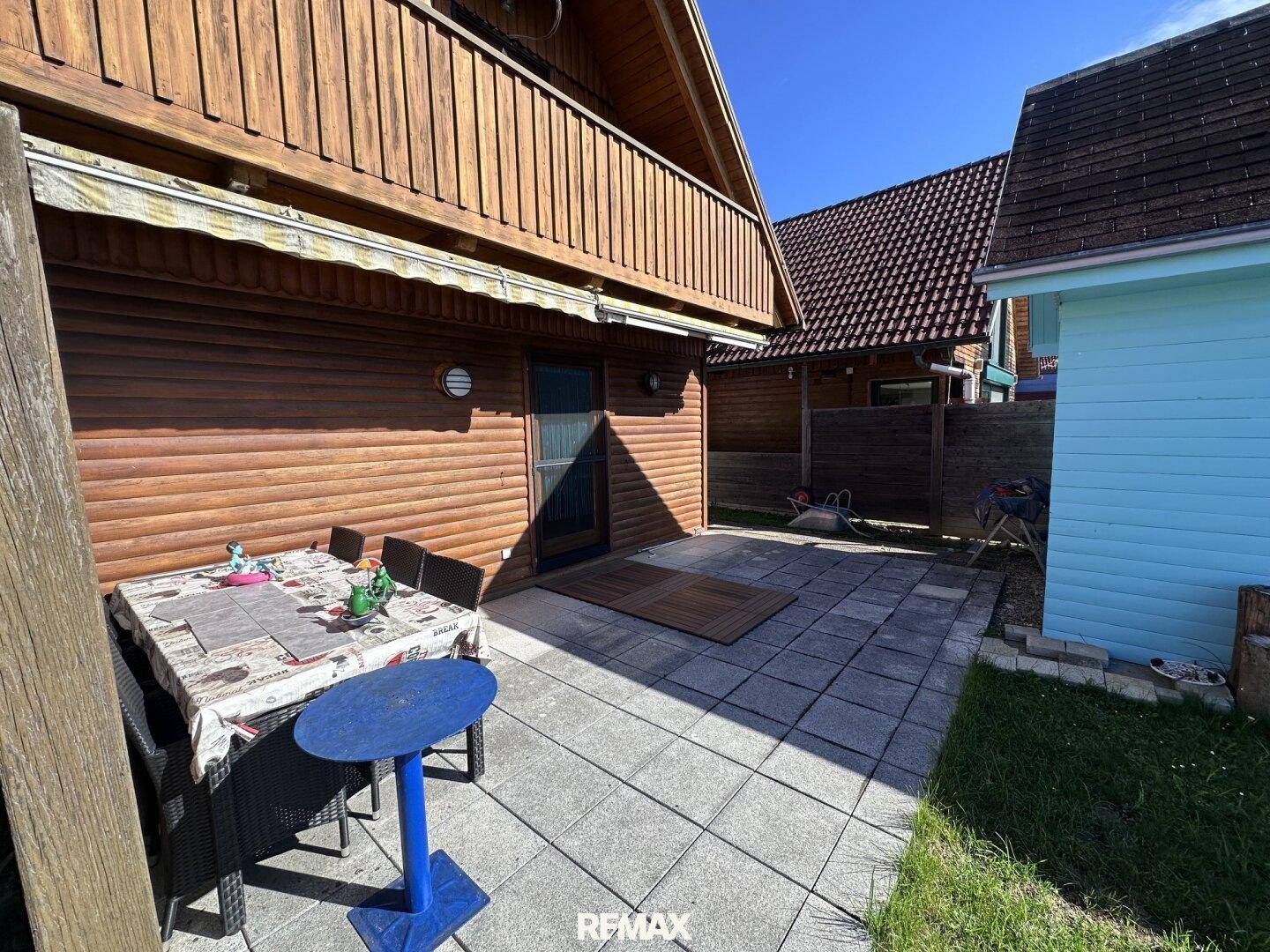 Geräumige gepflasterte Terrasse mit Gartenmöbeln neben dem Holzhaus, ideal für Mahlzeiten im Freien.