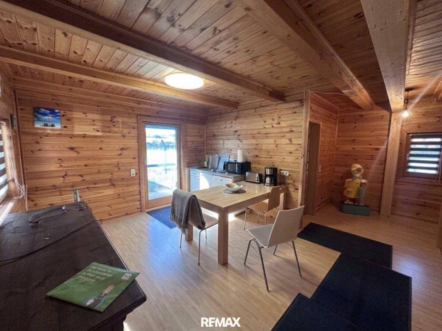 Rustikaler Wohn-Essbereich mit Holztäfelung, kleiner Küchenzeile und Esstisch.