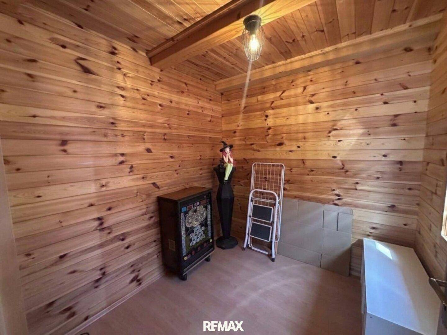 Gemütliches Schlafzimmer mit Holztäfelung und Laminatboden, derzeit als Abstellraum genutzt.