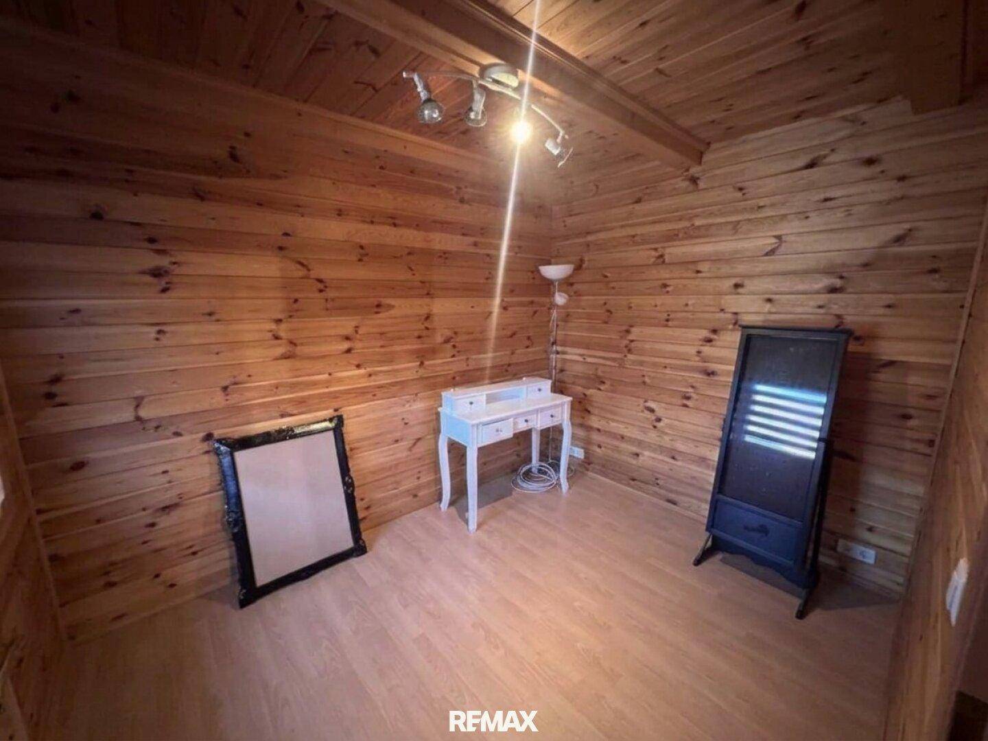 Helles Zimmer mit Holztäfelung, Laminatboden und einem kleinen Schreibtisch, ideal als Gästezimmer.