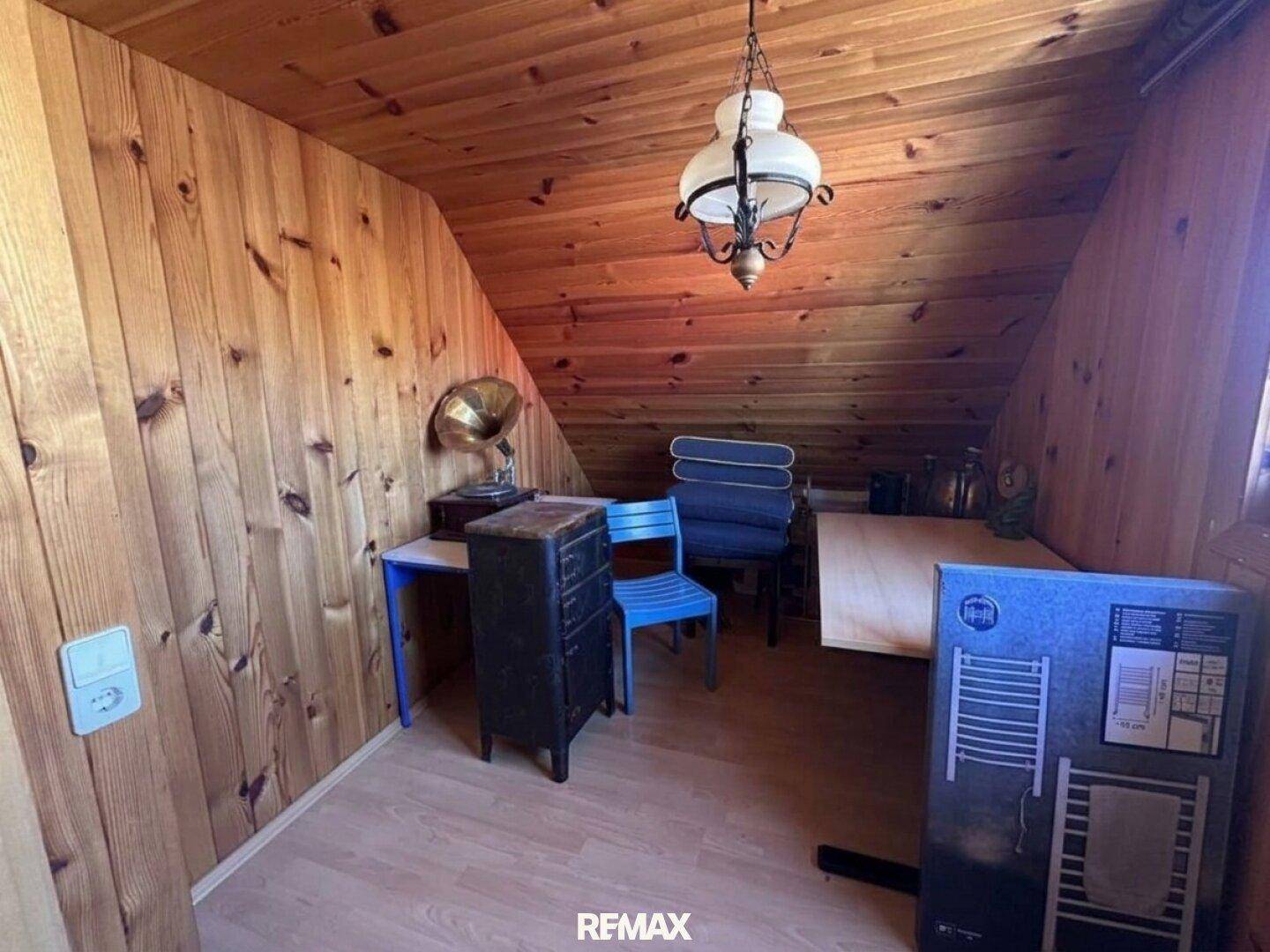 Dachgeschosszimmer mit Holztäfelung, schräger Decke und Laminatboden, ideal als Arbeits- oder Gästezimmer.