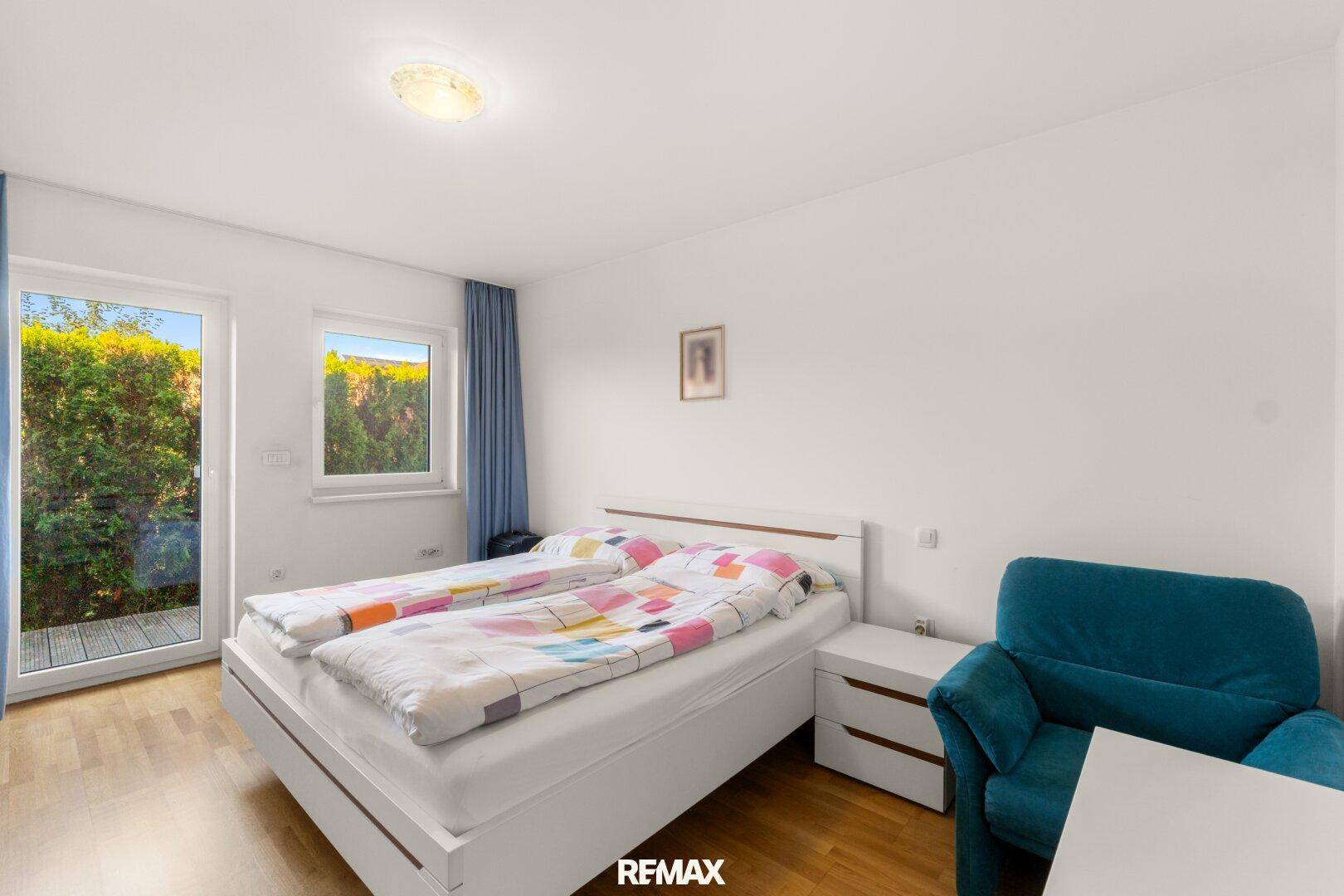 Helles Schlafzimmer mit Holzboden, Doppelbett und direktem Zugang zu einem Außenbereich.