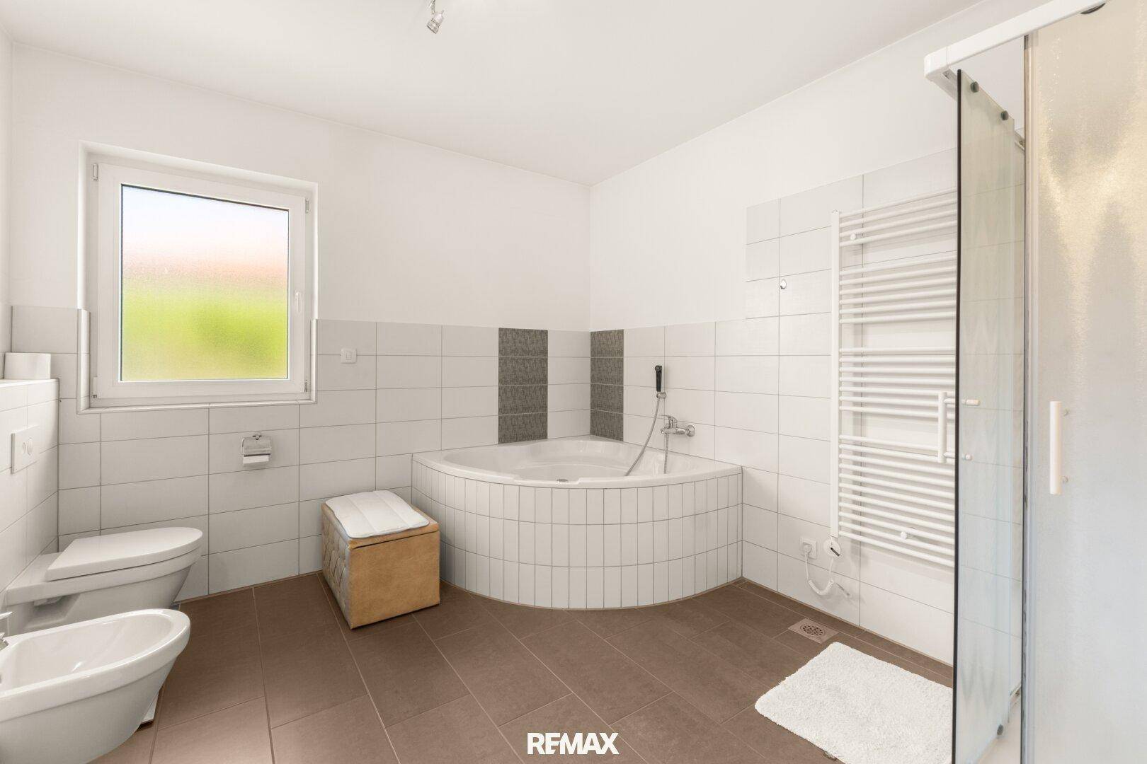 Geräumiges Badezimmer mit Eckbadewanne, separater Dusche, WC und beheiztem Handtuchhalter.